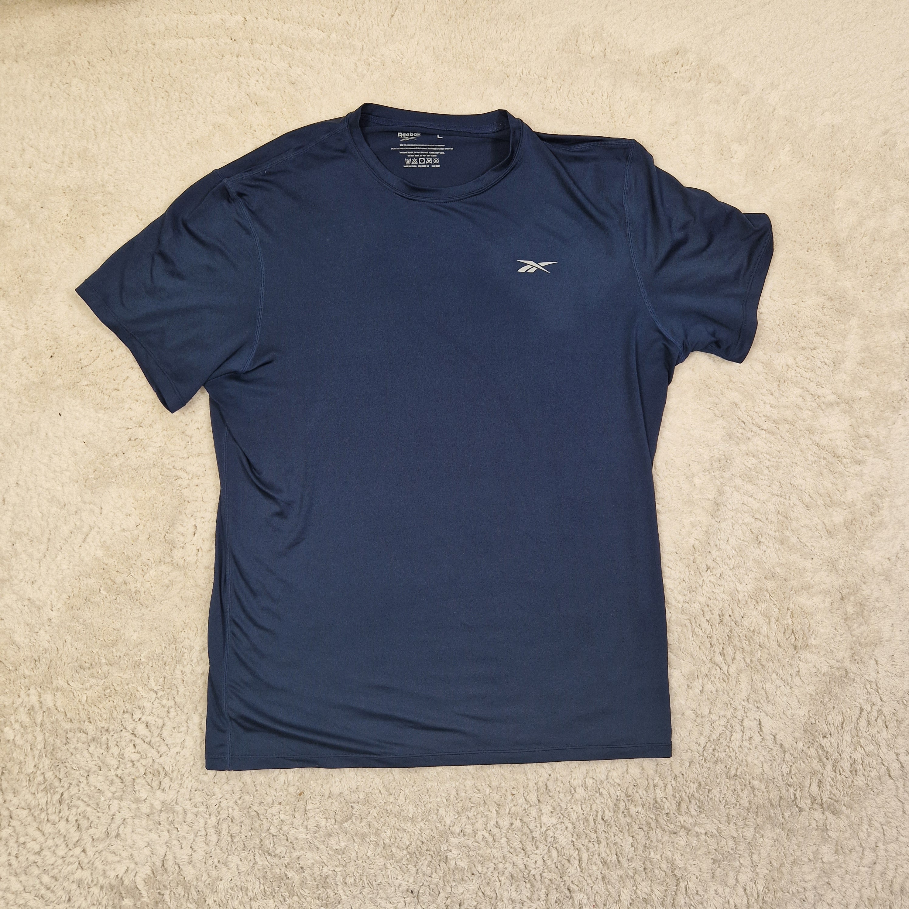 Blue athletic shirt with a brand logo on a beige carpet