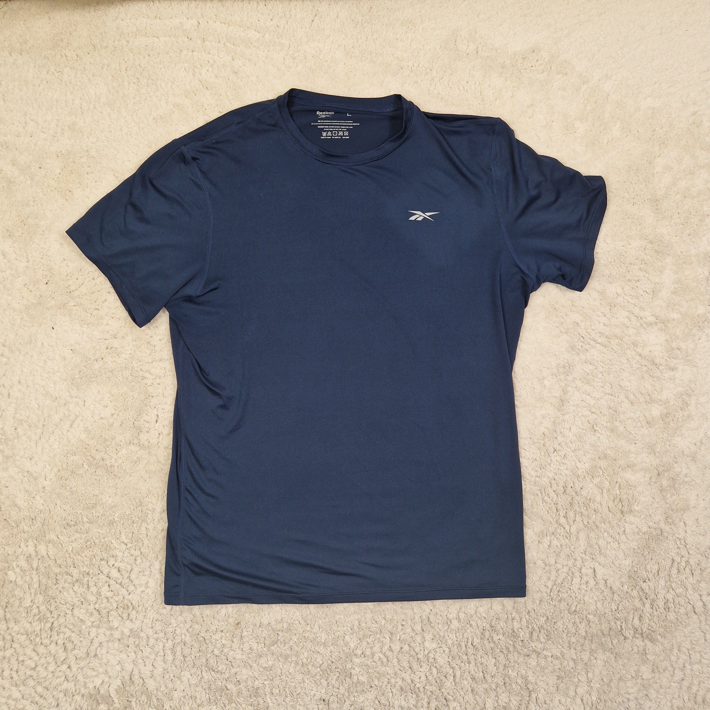 Blue t-shirt with a logo on a beige carpet