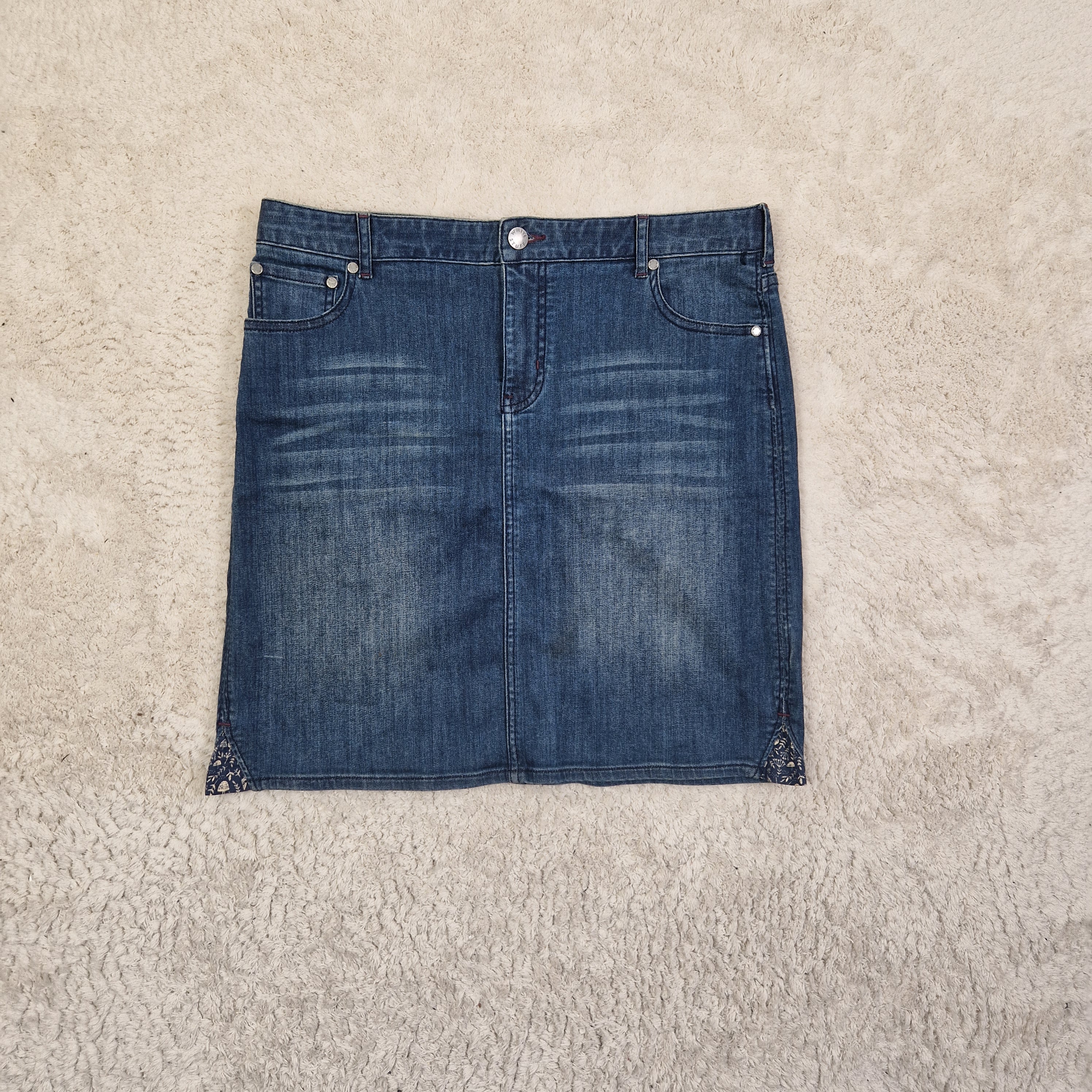 Folded blue denim jeans on a beige carpet