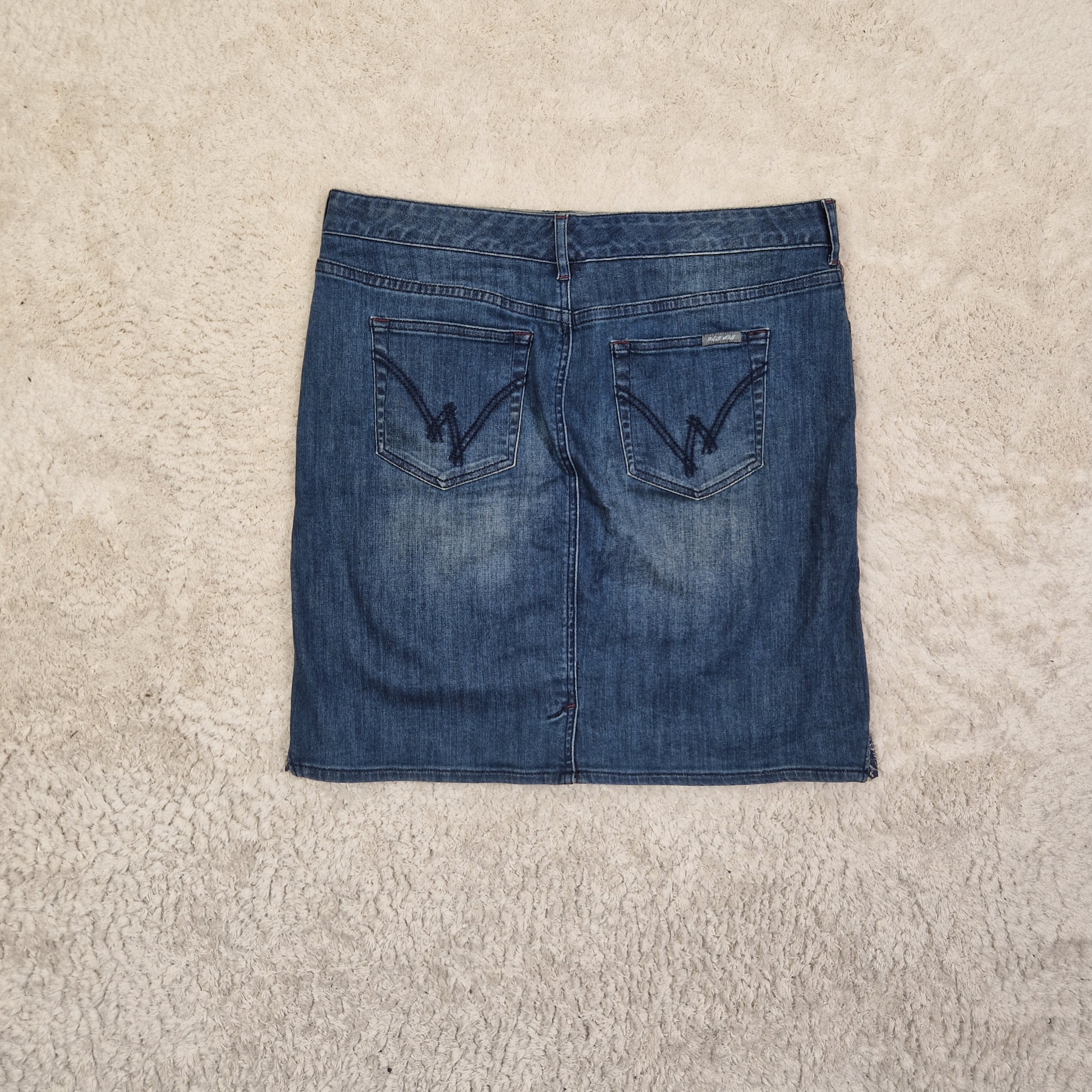 Folded blue denim jeans on a beige carpet