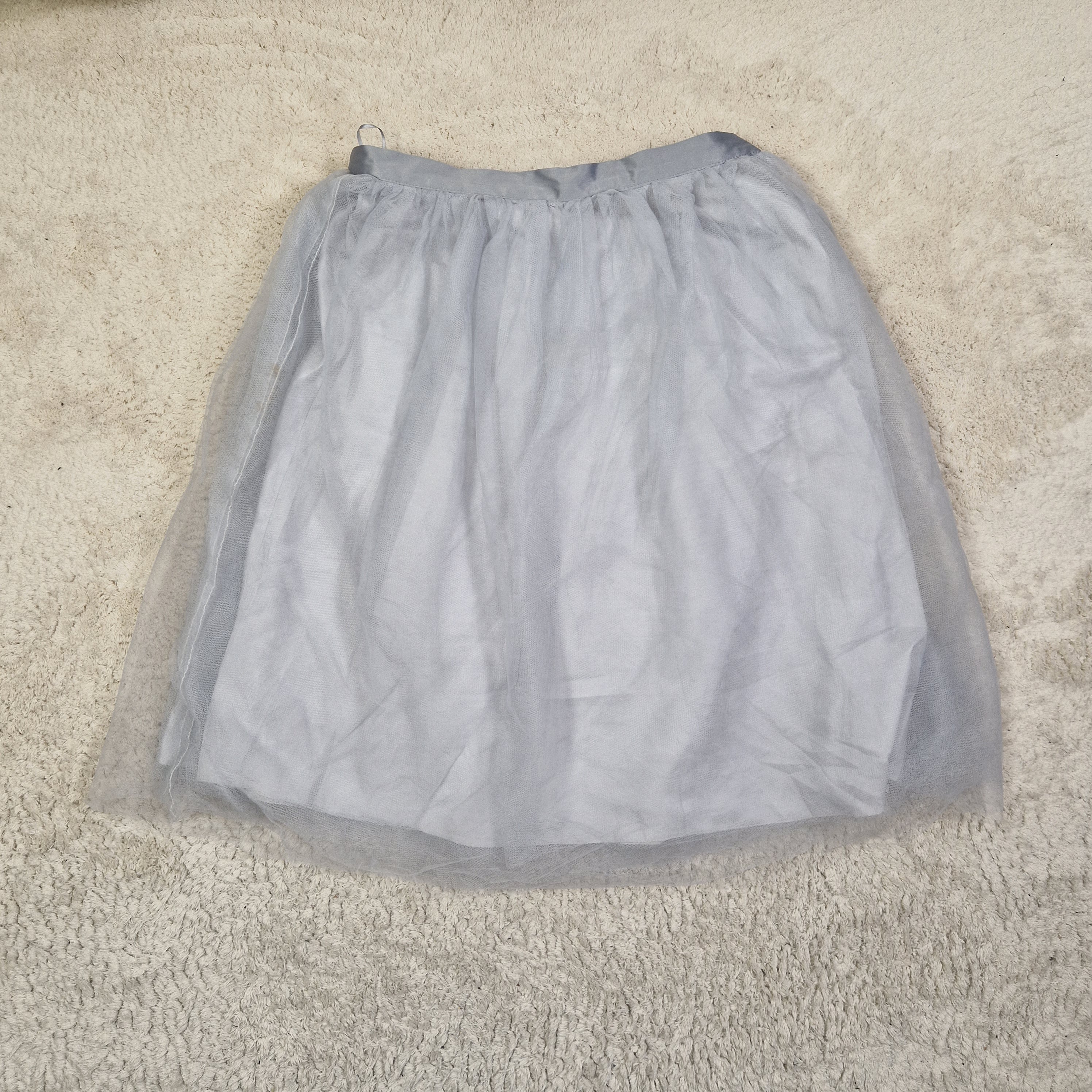 Folded light gray shirt on a beige carpet