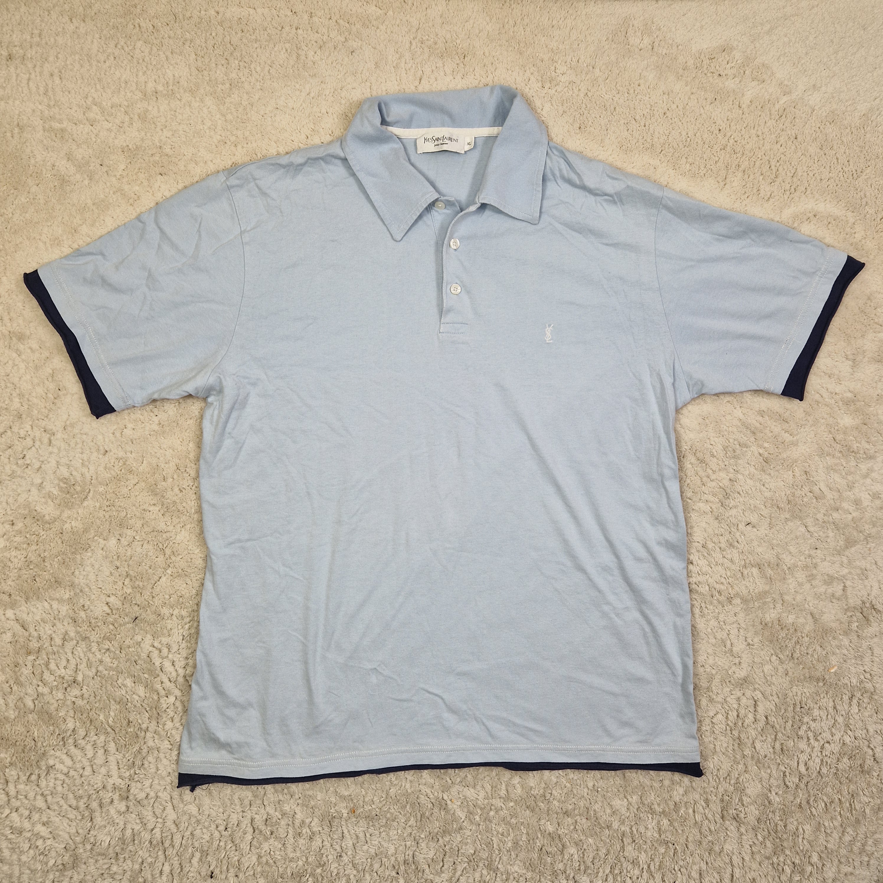 Light blue shirt with dark trim on a beige carpet