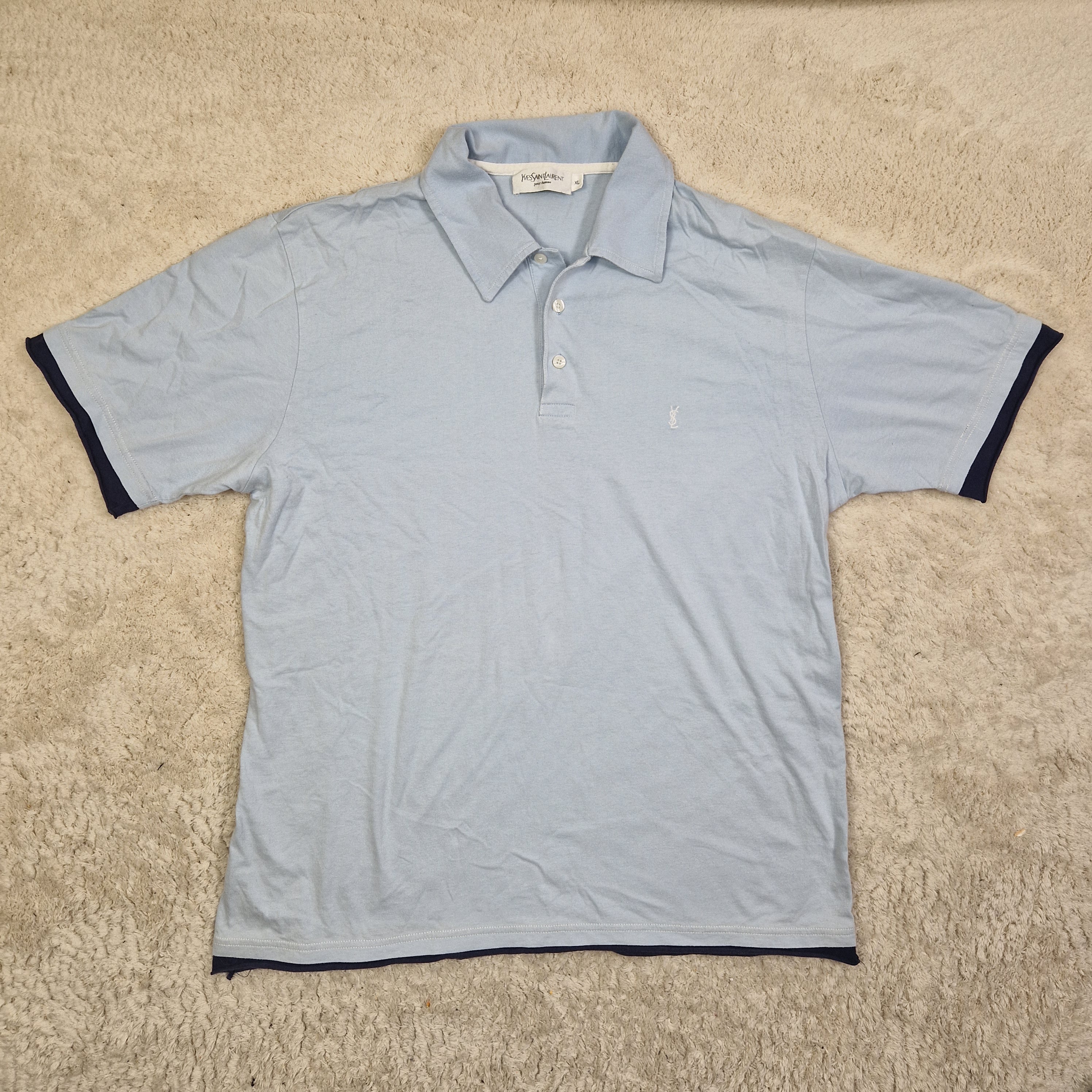 Light blue shirt with black trim on a beige carpet