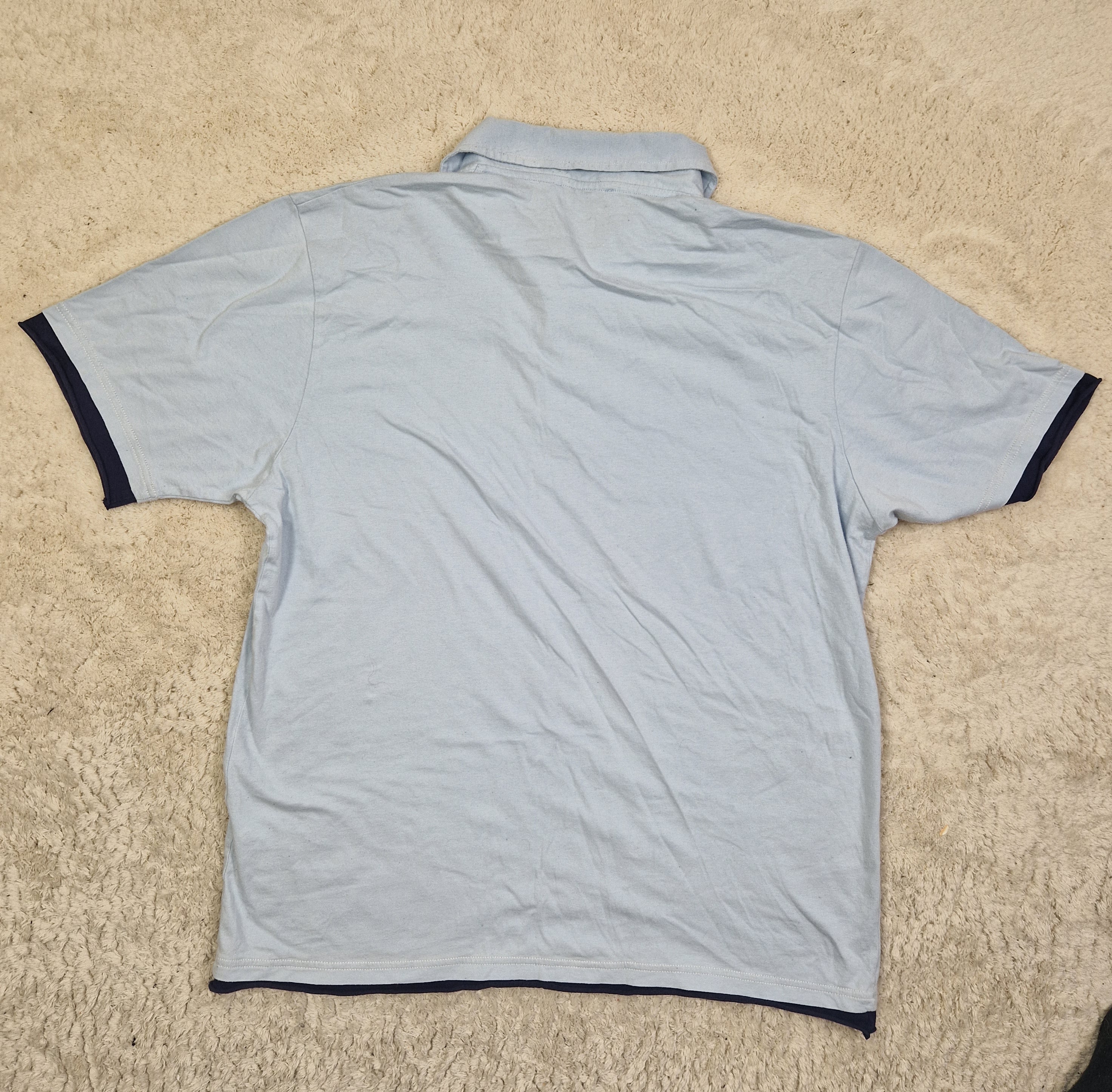 Light blue shirt with black trim on a beige carpet
