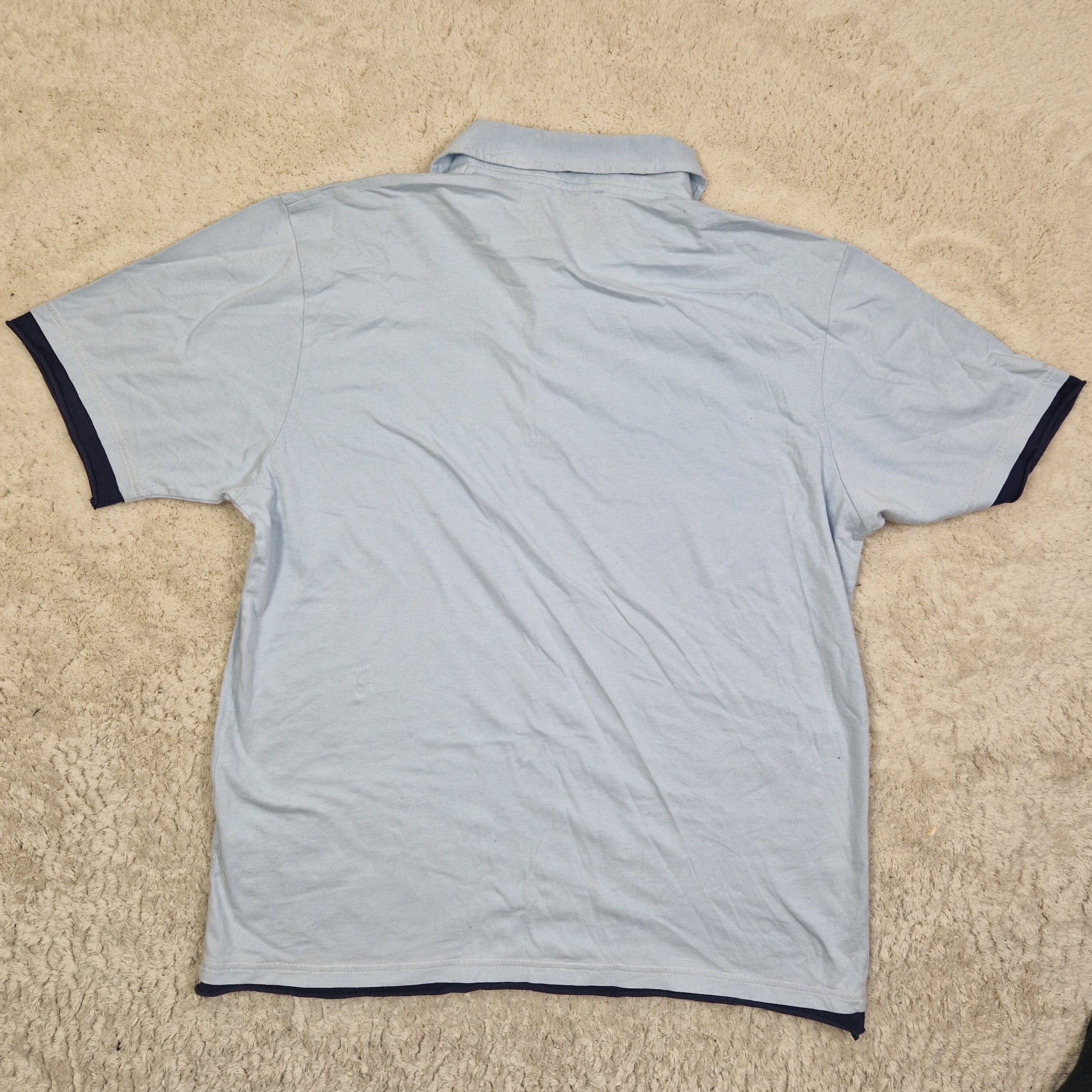 Light blue shirt with black trim on a beige carpet