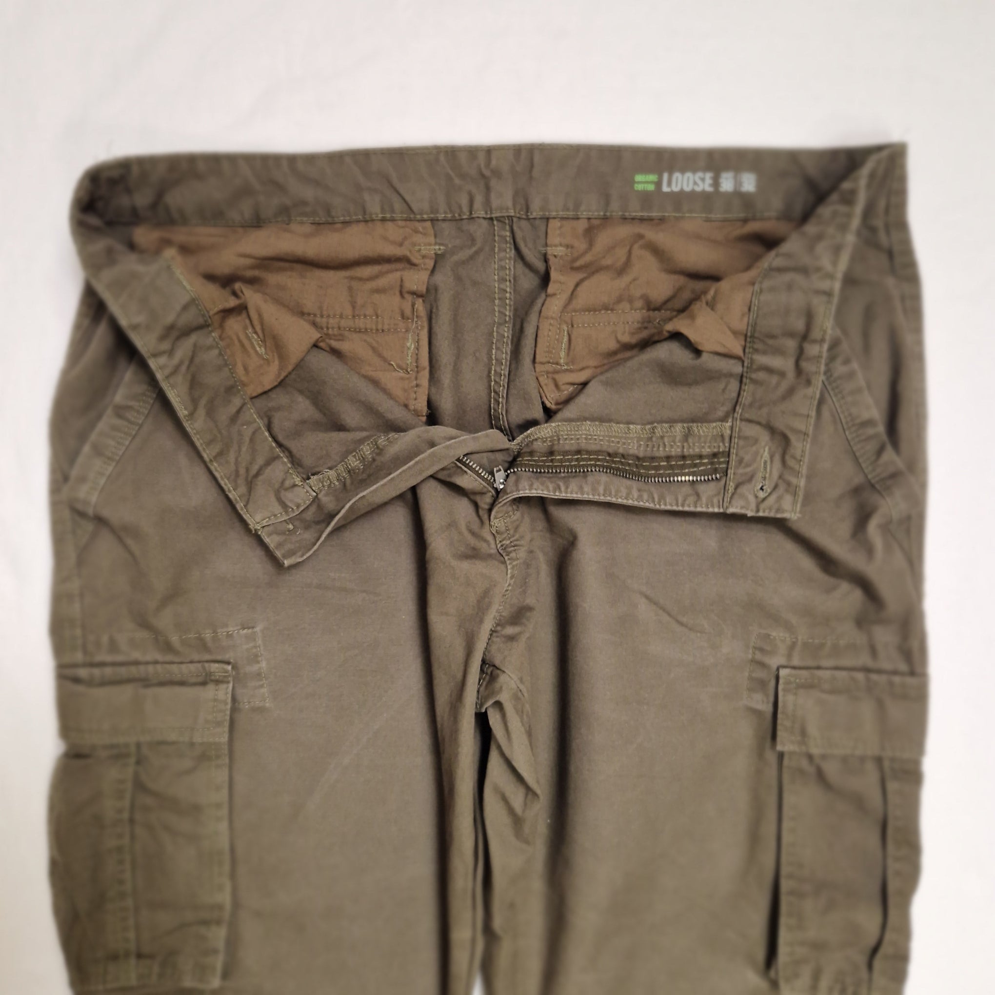 A pair of loose-fit cargo pants in an olive drab or khaki green color, laid flat on a white background. The waistband features a distinctive zippered front closure with a drawstring tie, and the brand name 'LOOSE' is visible inside the waistband.