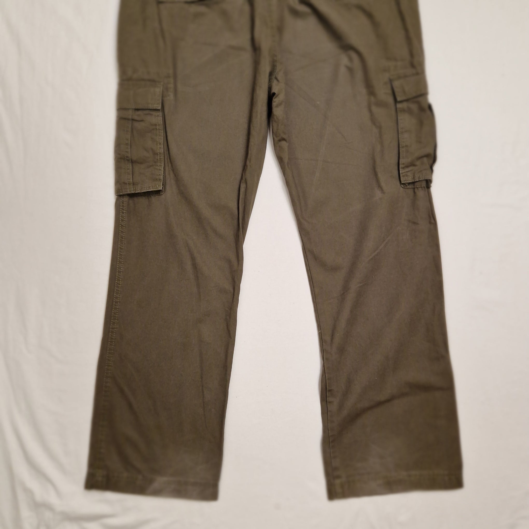 A pair of olive green cargo pants laid flat on a white fabric background.