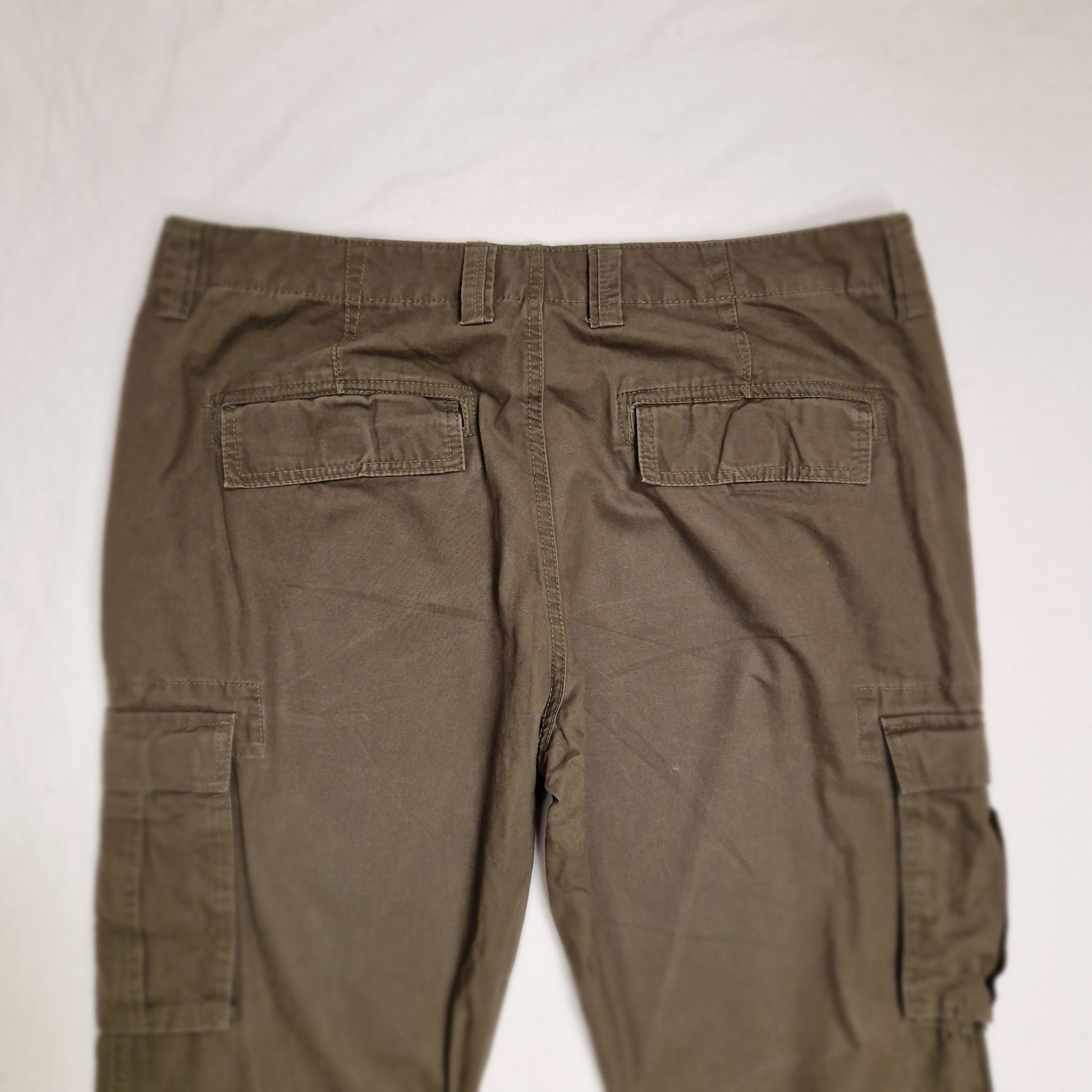A pair of olive green cargo pants laid flat on a white background, showing the back side with multiple flap pockets.