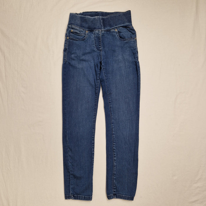 A pair of medium wash blue denim jeans laid flat on a light beige fabric background.