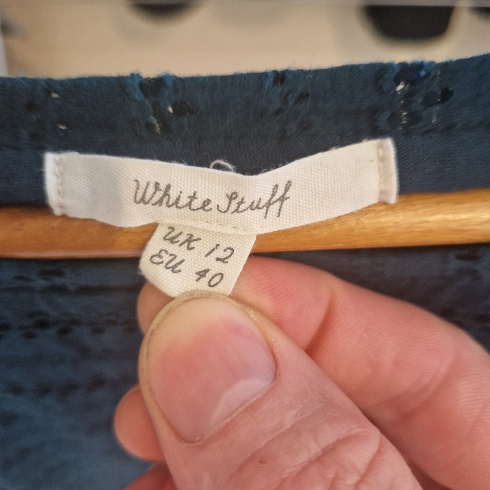 A close-up of a White Stuff brand label on a navy blue embroidered floral dress, size UK 12.