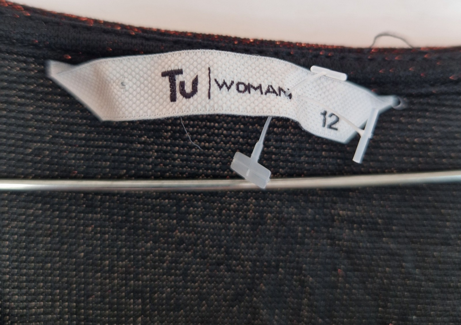 A close-up of a maroon glittery long-sleeve top with a Tu Woman size 12 clothing label.