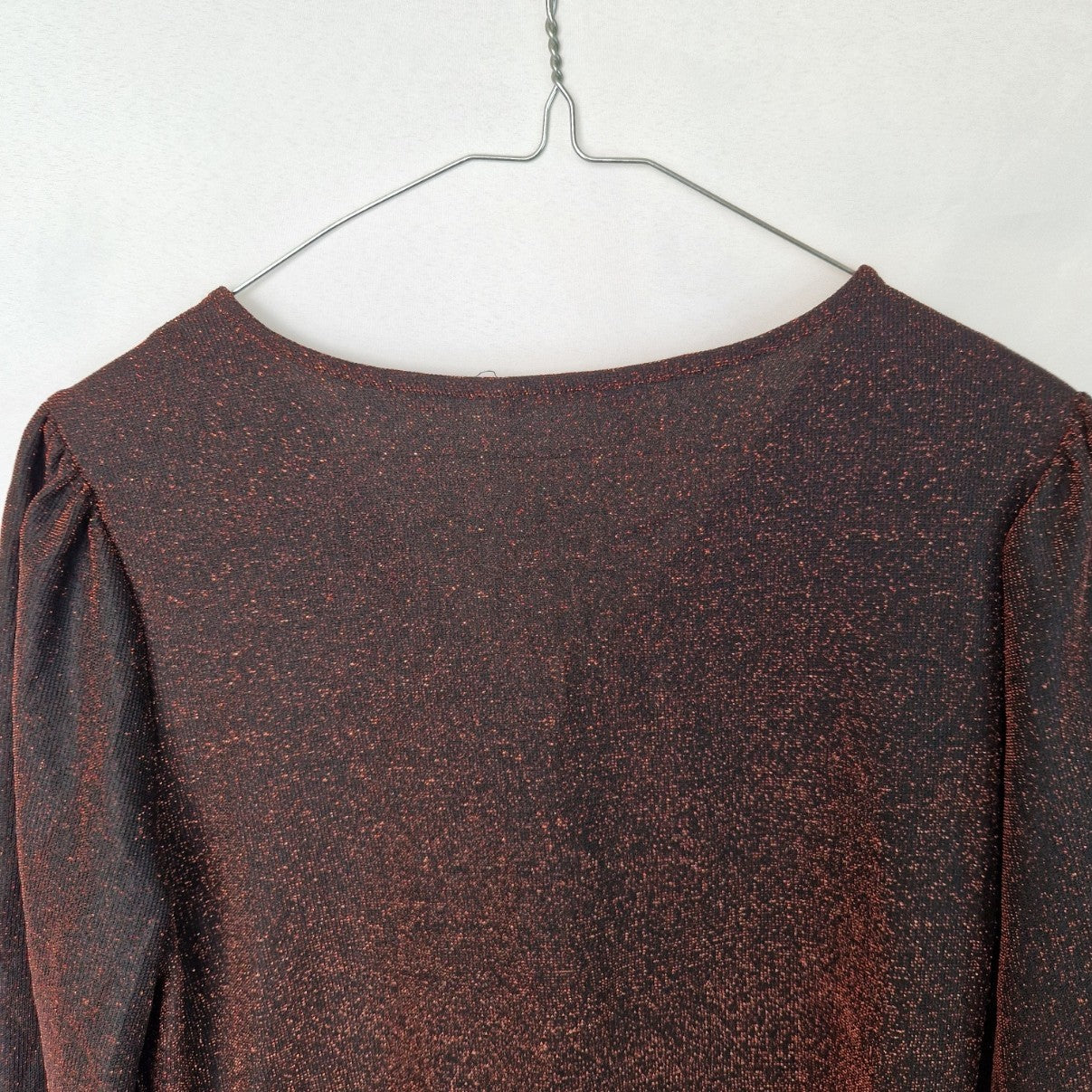 A maroon long-sleeve top with a subtle glitter finish and a V-neckline.
