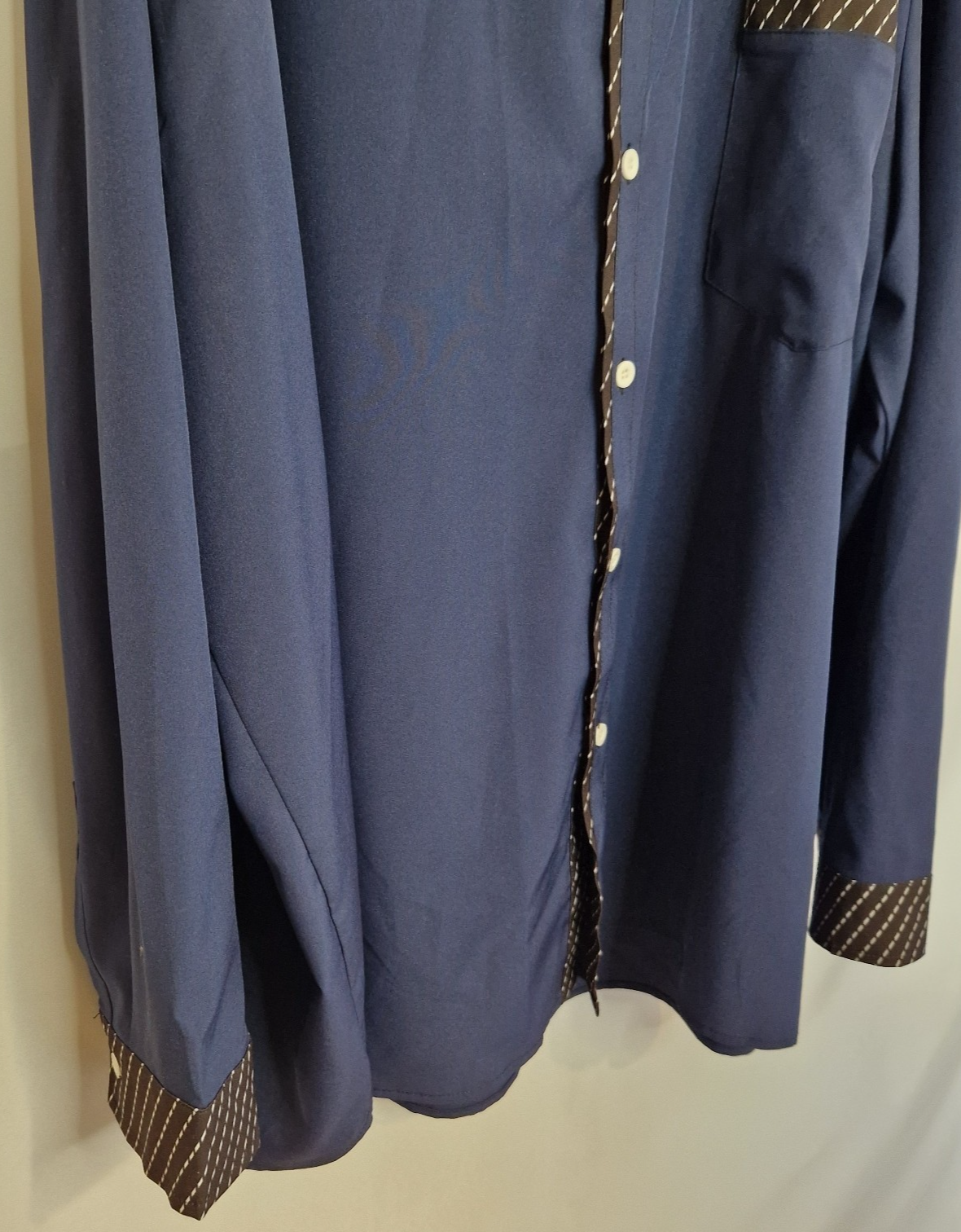A blue long-sleeve men's shirt featuring brown patterned contrast trim on the cuffs and placket.