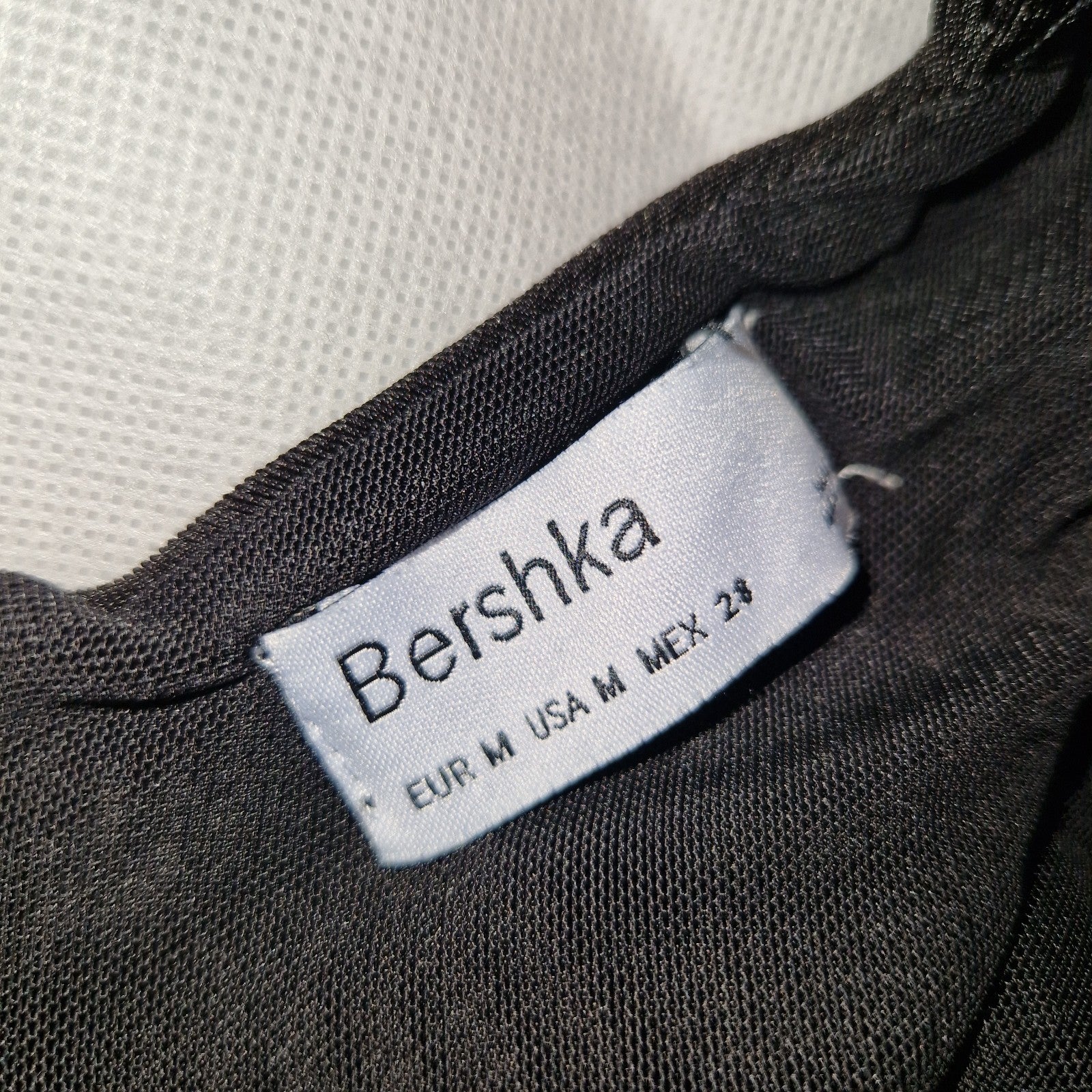 A black Bershka crop top with a size tag indicating EUR M and USA M.