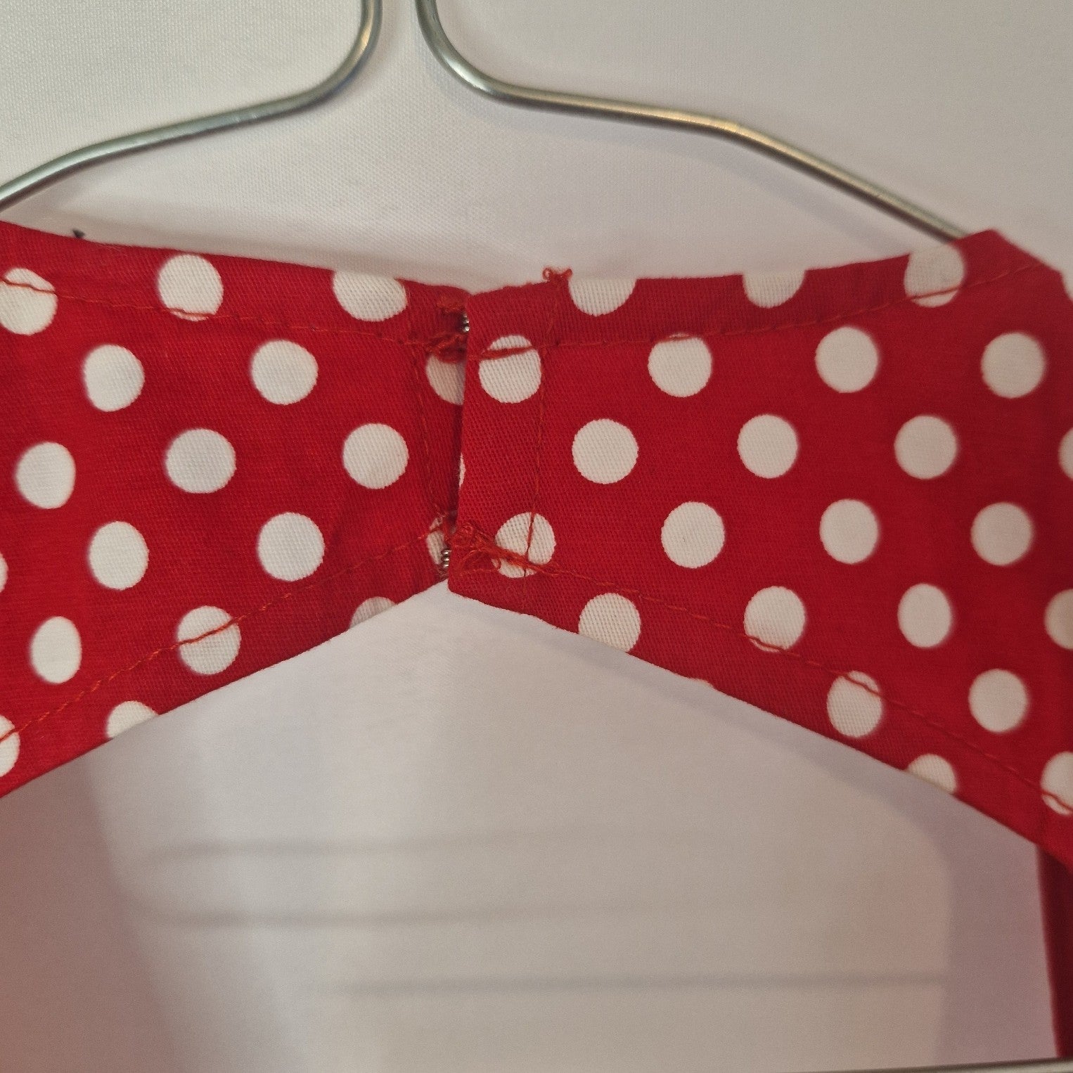 A close-up view of the red and white polka dot halter neck closure on a vintage-style dress.
