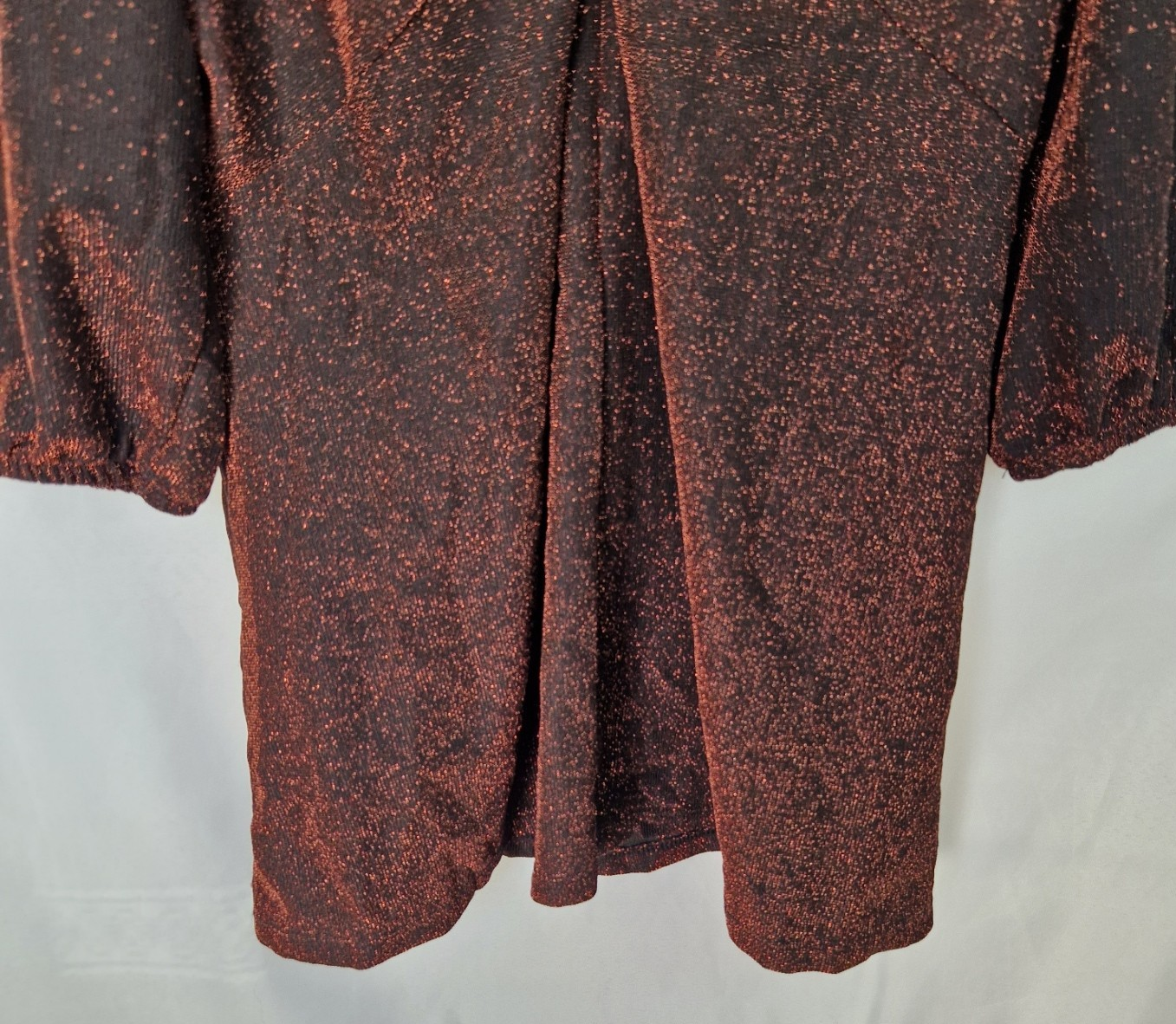 A maroon long-sleeve top with a glitter finish and a draped twist-front detail.