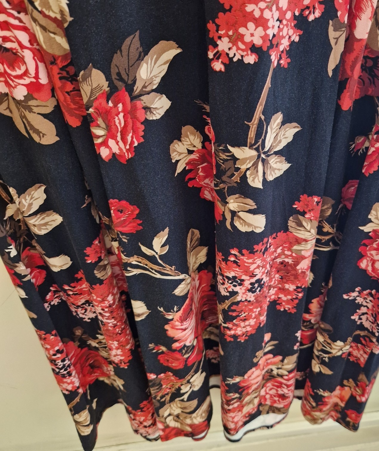A black fit and flare dress featuring a vibrant red floral print and long flared sleeves.