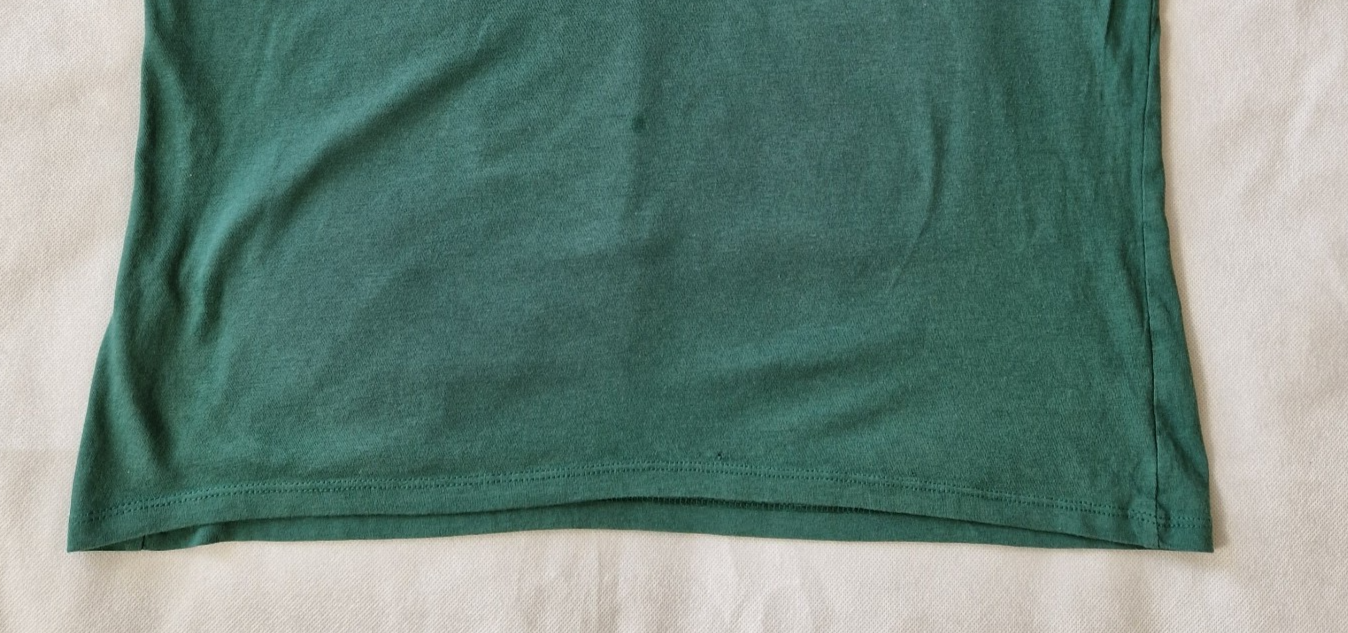 A close-up view of the hemline of a green H&M Divided cotton jersey t-shirt.