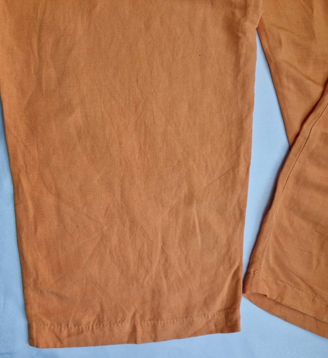 A close-up view of the hem and fabric texture of orange H&M wide-leg jogger trousers.