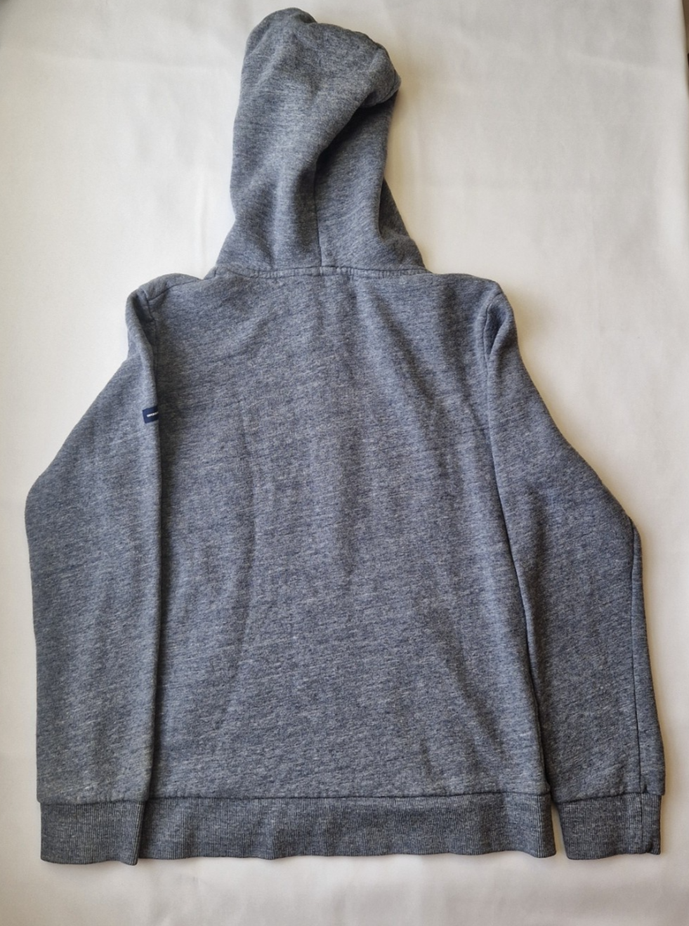 A grey Superdry boys pullover hoodie with a hood and ribbed cuffs shown from the back.