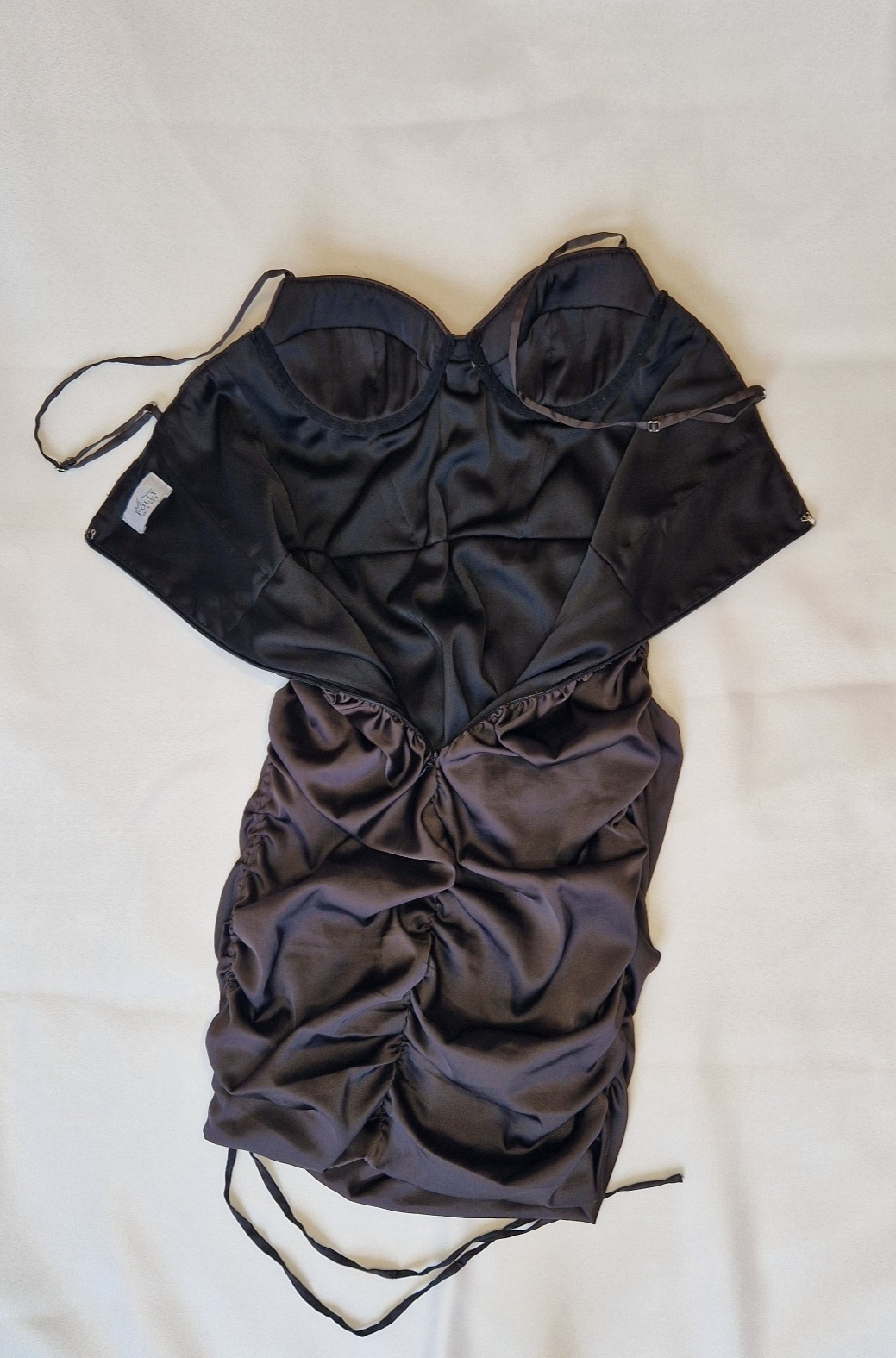 A black Oh Polly satin bodycon mini dress with a ruched finish and structured bodice.