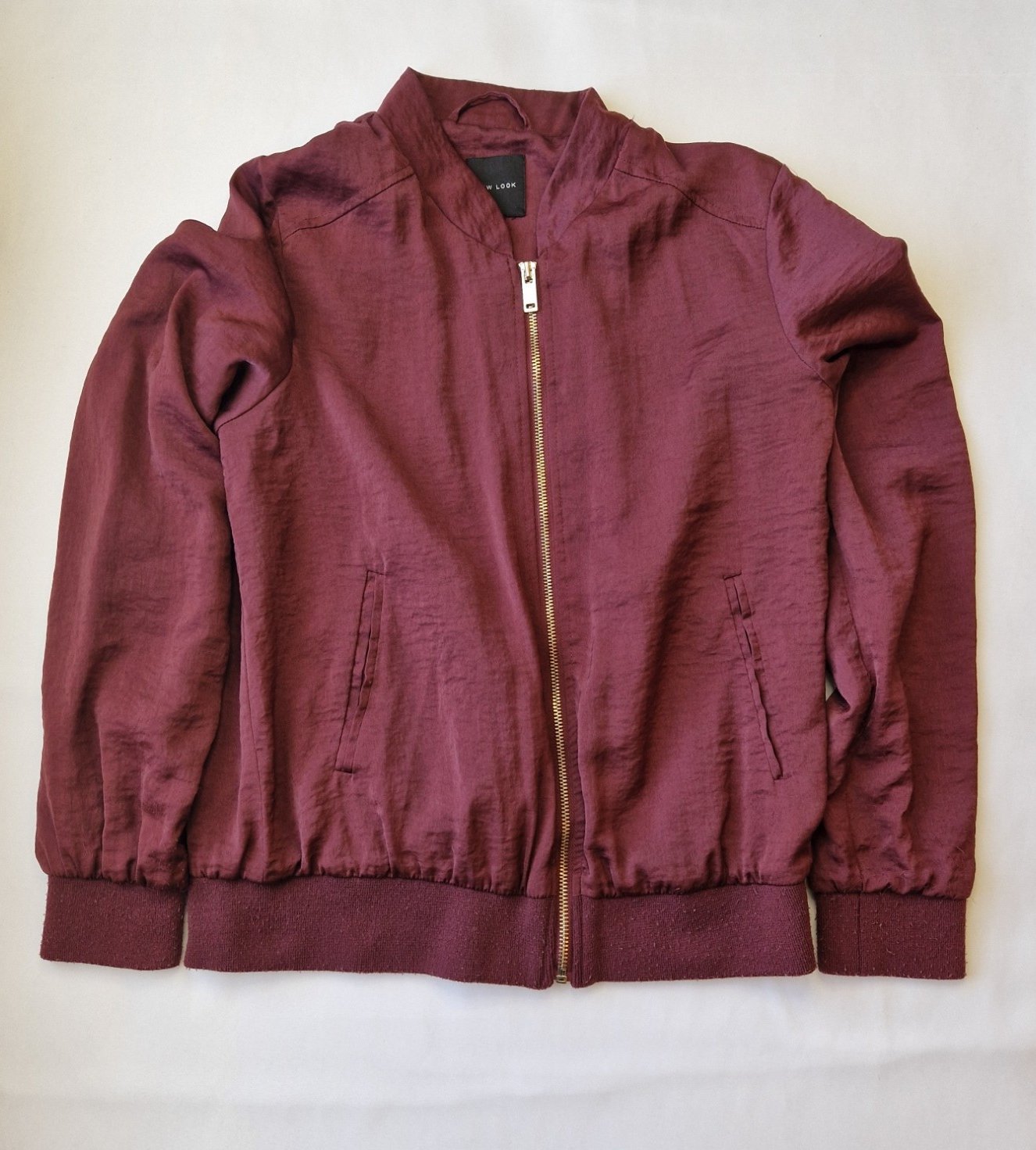 A maroon New Look lightweight bomber jacket with a full zip closure and ribbed cuffs.
