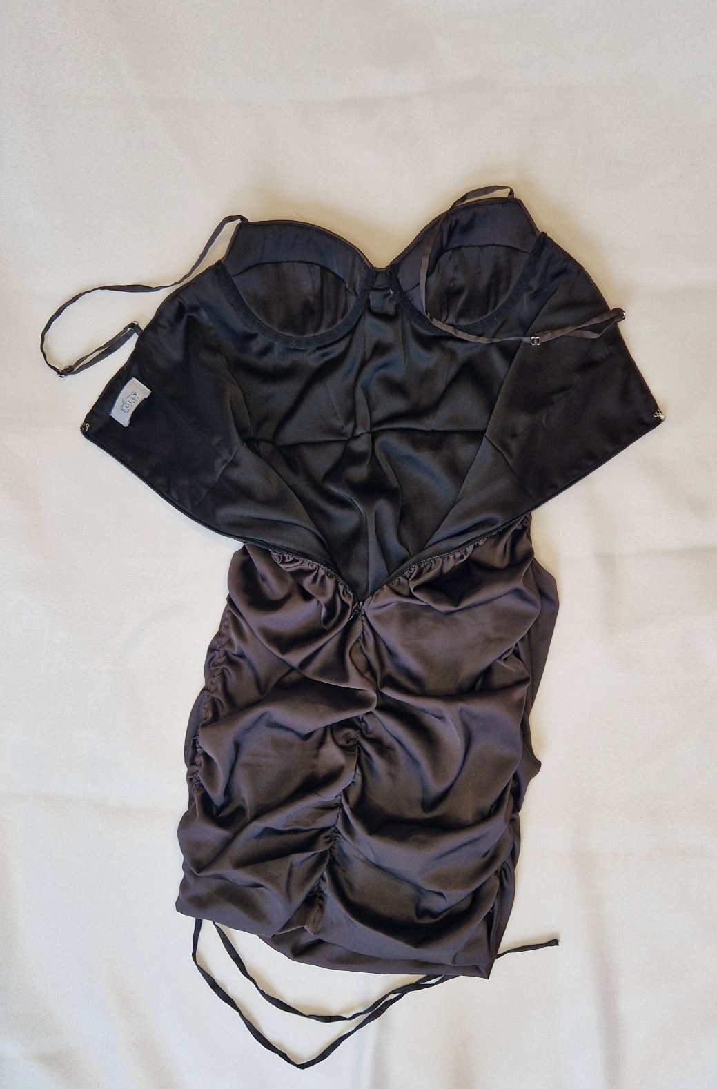 A black Oh Polly satin bodycon mini dress with a ruched finish and off-the-shoulder neckline.