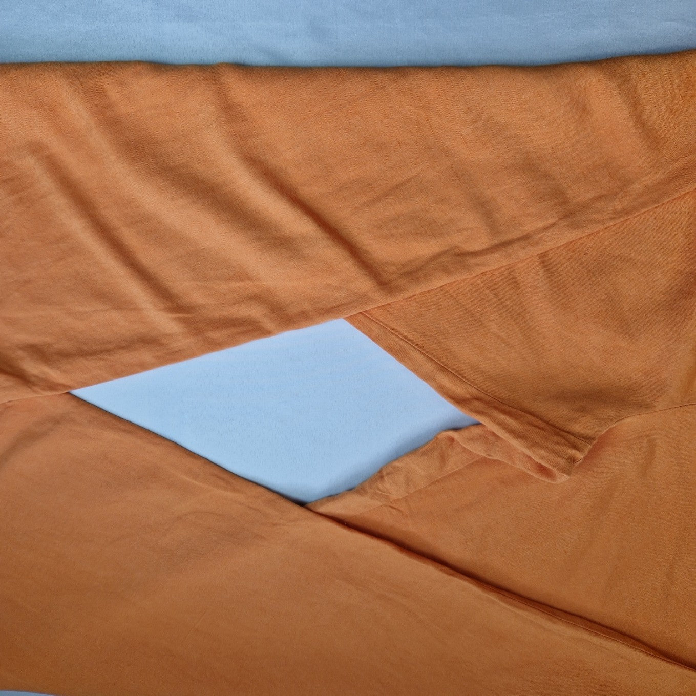 Close-up of orange linen-blend wide-leg jogger trousers with a visible light blue background.