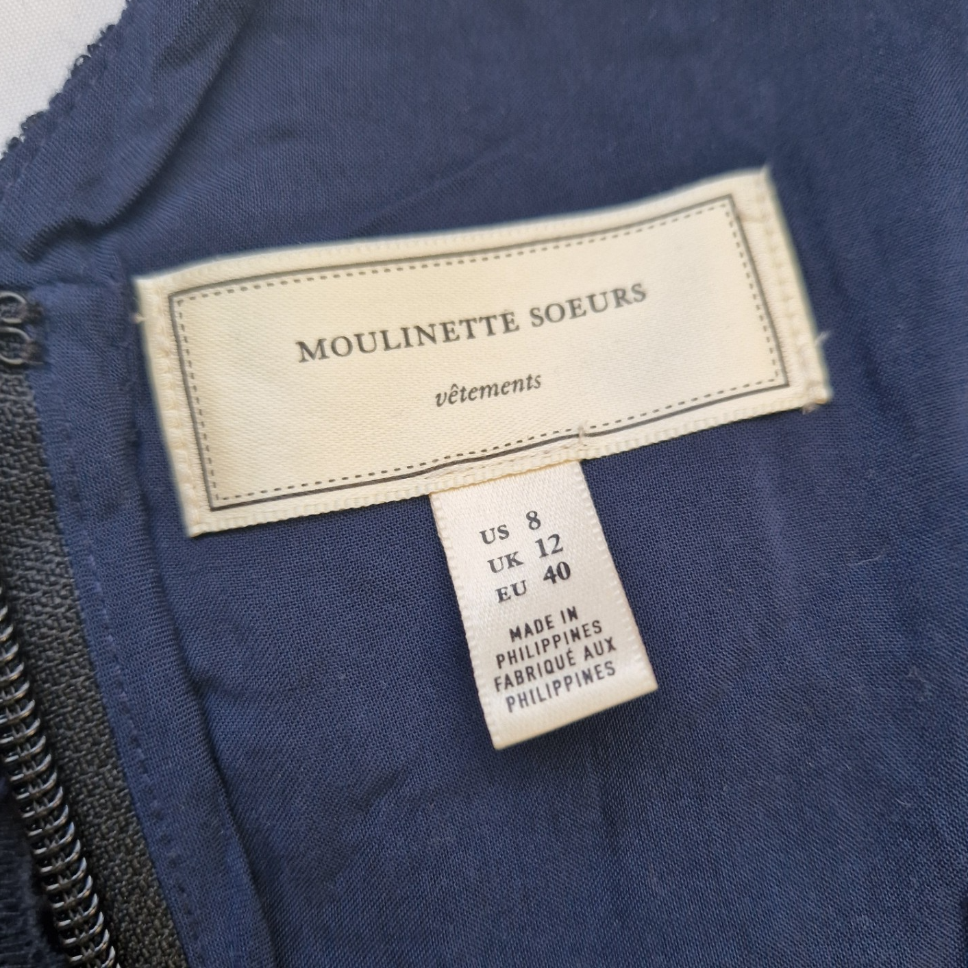 A close-up of a Moulinette Soeurs clothing label inside a blue dress, showing size UK 12.