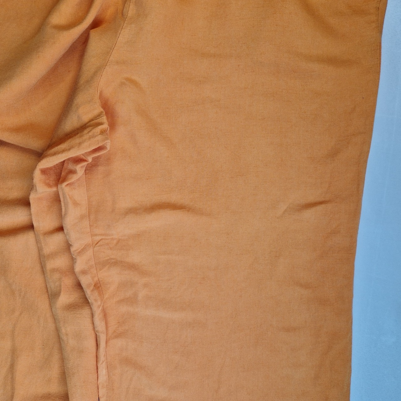 Close-up of orange H&M wide-leg jogger trousers in a lightweight linen-blend fabric.