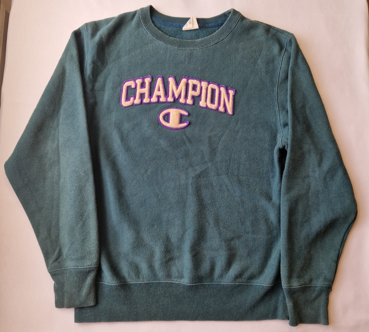 A green Champion cotton pullover sweatshirt with a purple and cream embroidered logo.