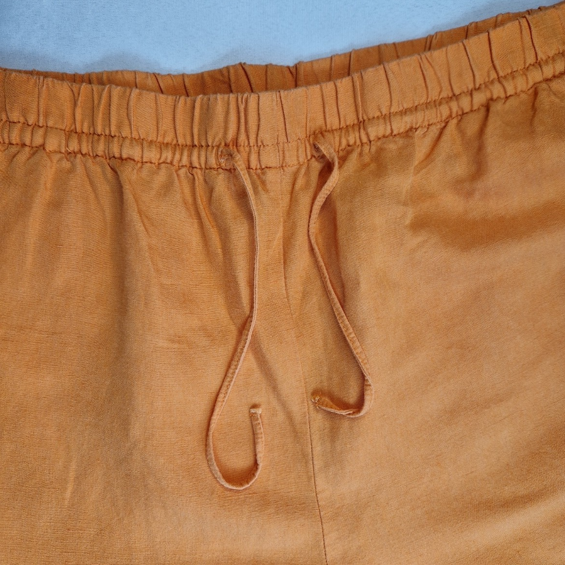 Close-up of orange H&M wide-leg jogger trousers featuring an elasticated drawstring waist.