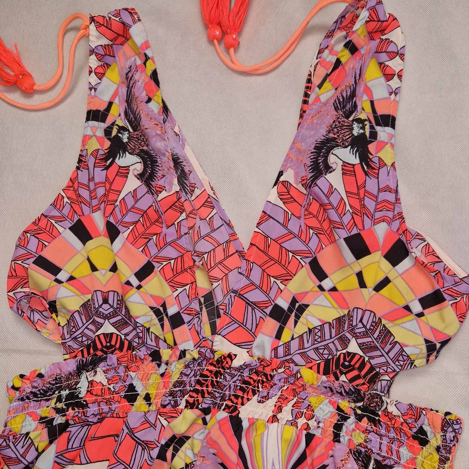 A multicoloured floral print playsuit with an off-the-shoulder neckline and tassel tie accents.