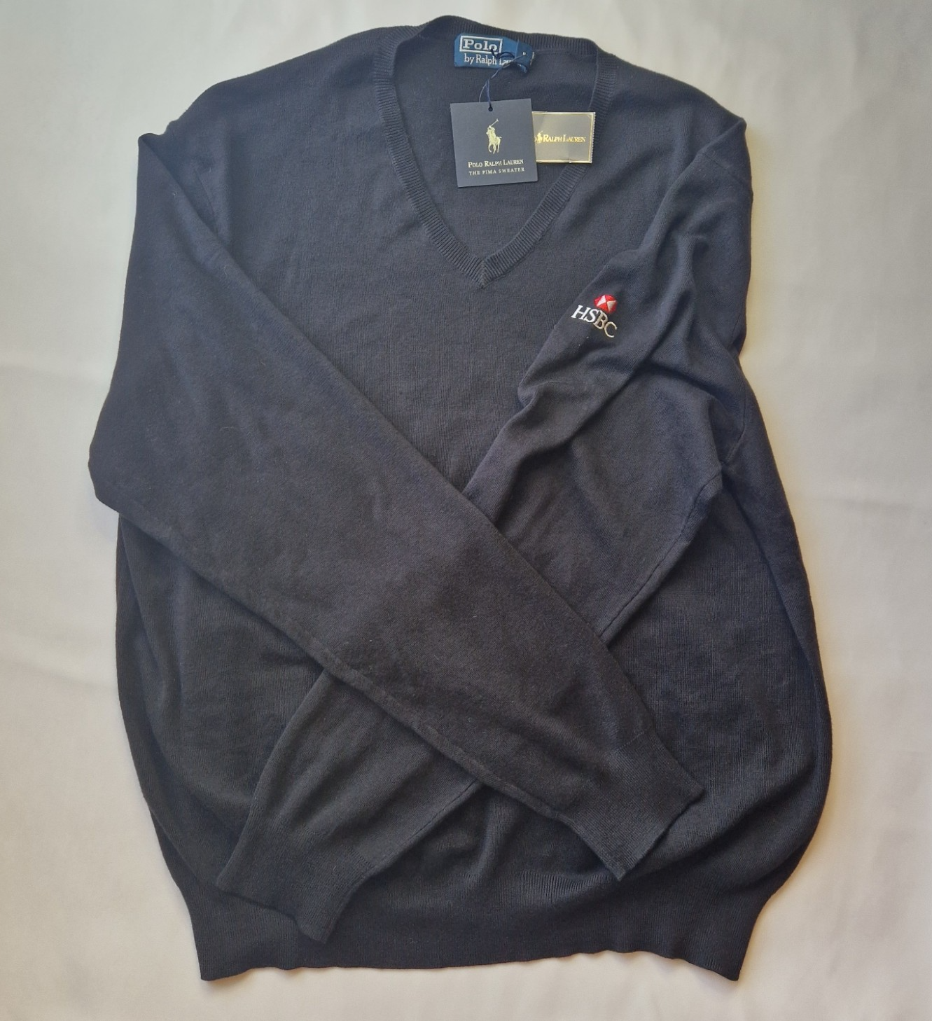 A black Ralph Lauren V-neck cotton sweater featuring an embroidered HSBC logo on the sleeve.