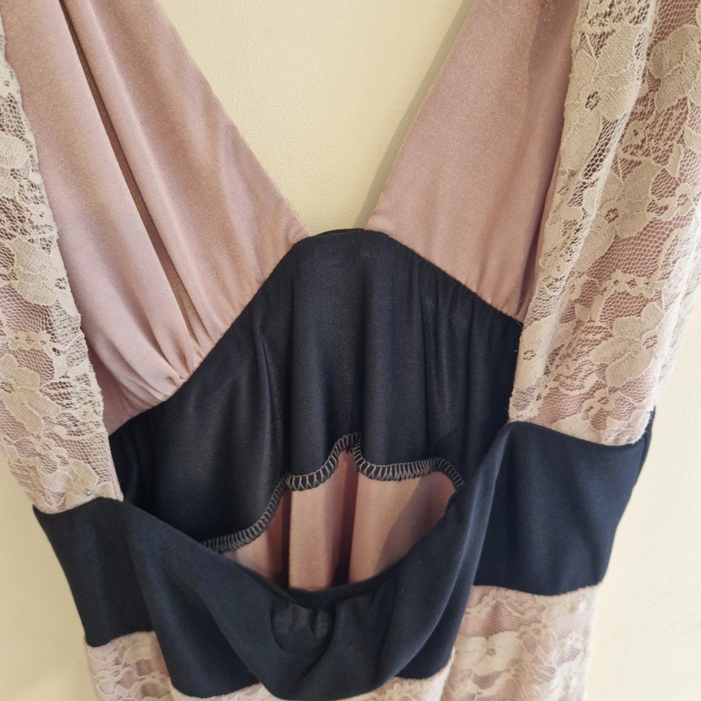 A pink lace ball gown featuring a deep V-neckline and a black waist panel with cut-out detailing.