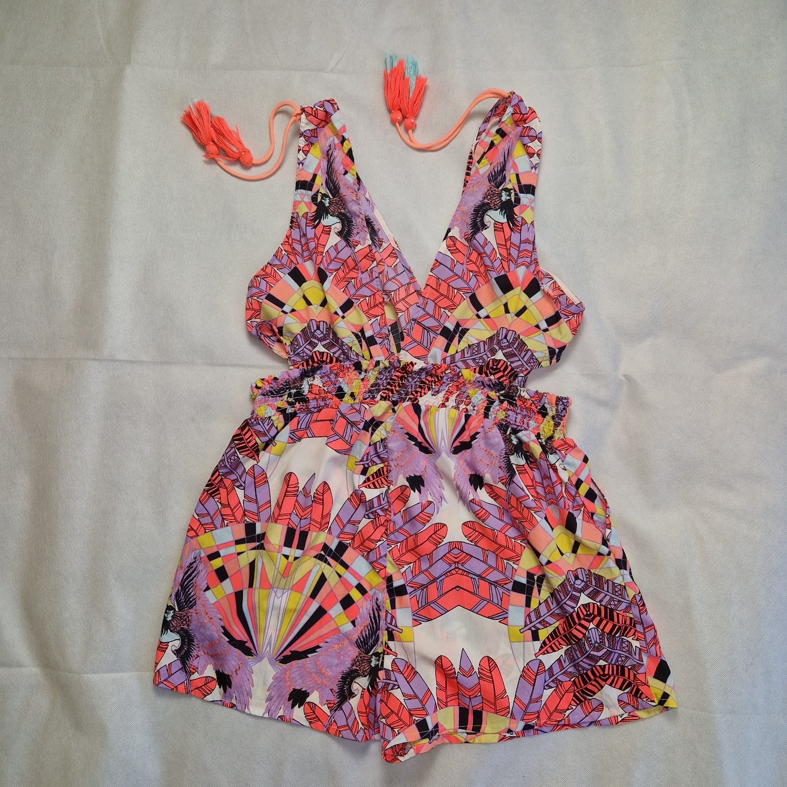A multicoloured floral print playsuit with a deep V-neck, tassel ties, and an elasticated waist.