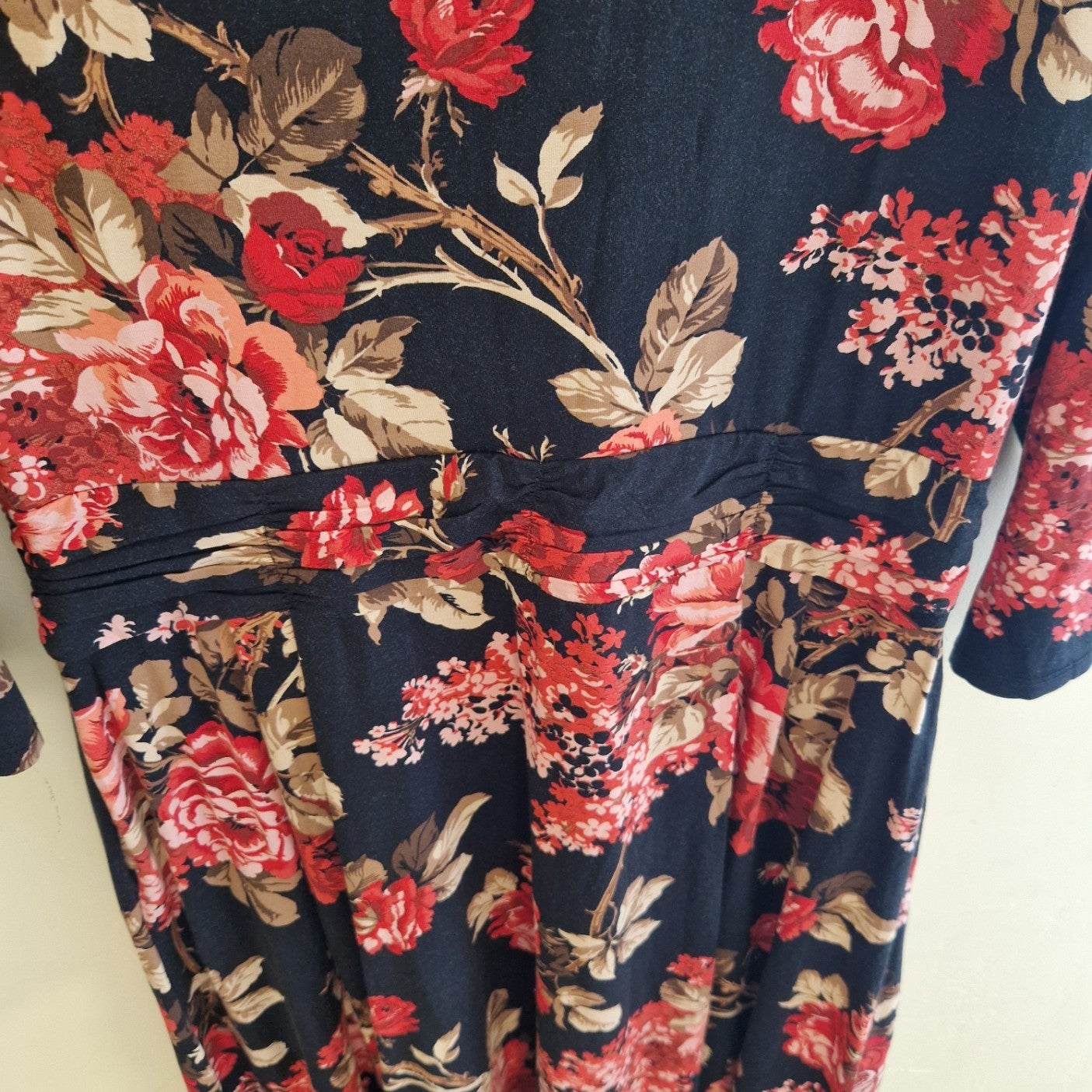 A black fit and flare dress featuring a vibrant red and beige floral print and long sleeves.
