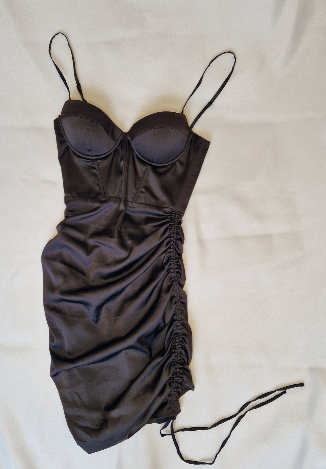 A black satin bodycon mini dress with a structured corset bodice and ruched side detailing.