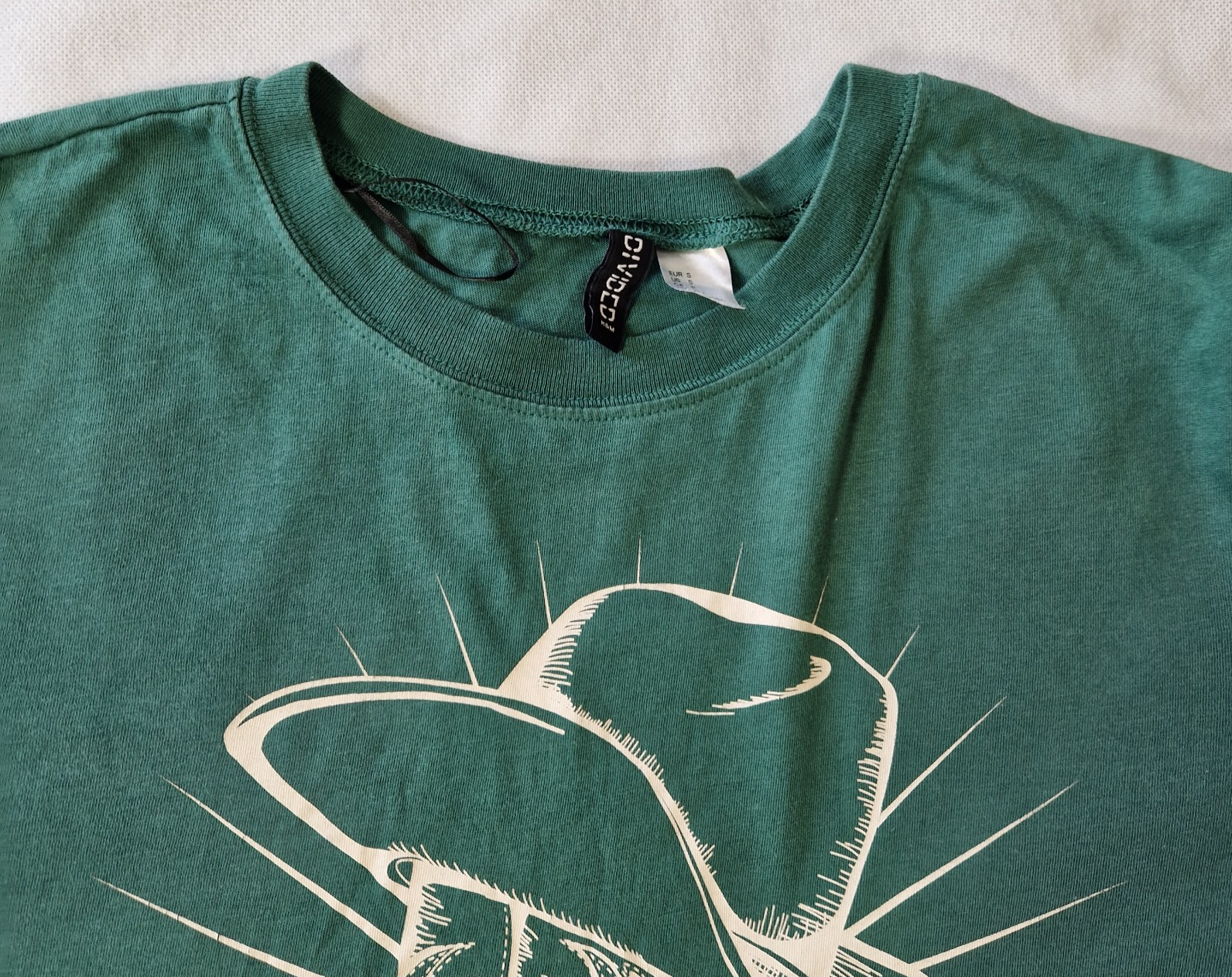 A green H&M Divided cotton t-shirt with a crew neck and a white graphic print of a cowboy hat.