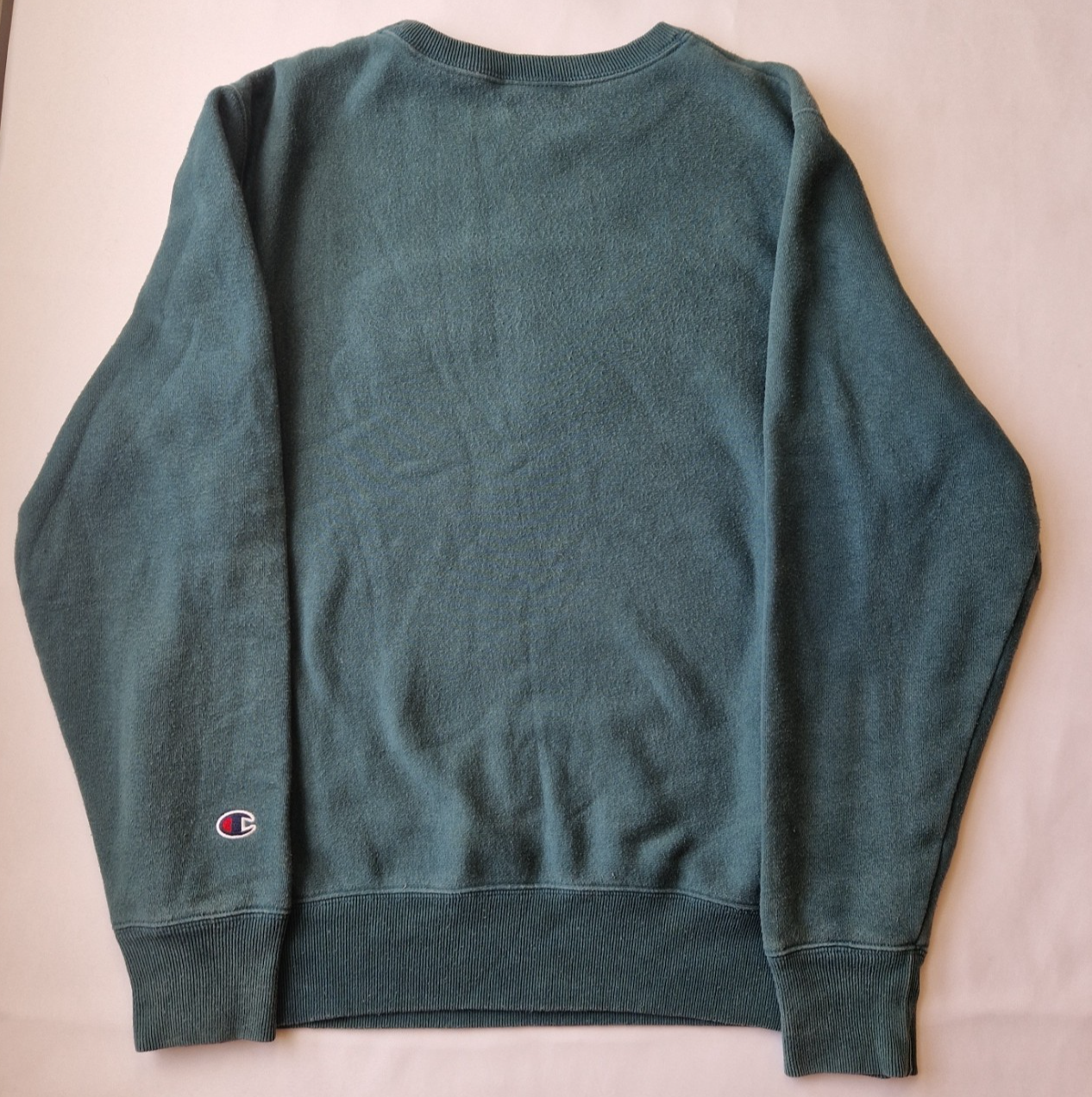 A green Champion cotton pullover sweatshirt with a round neck and an embroidered logo on the sleeve.