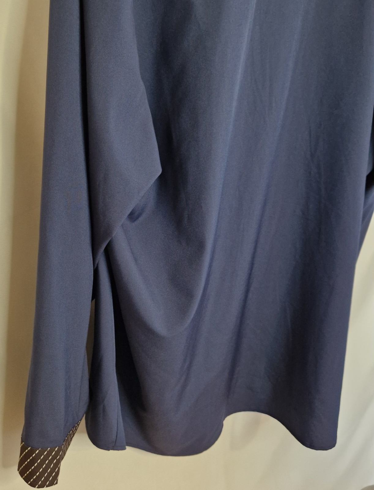 A blue long-sleeve satin shirt featuring a brown patterned contrast trim on the cuffs.
