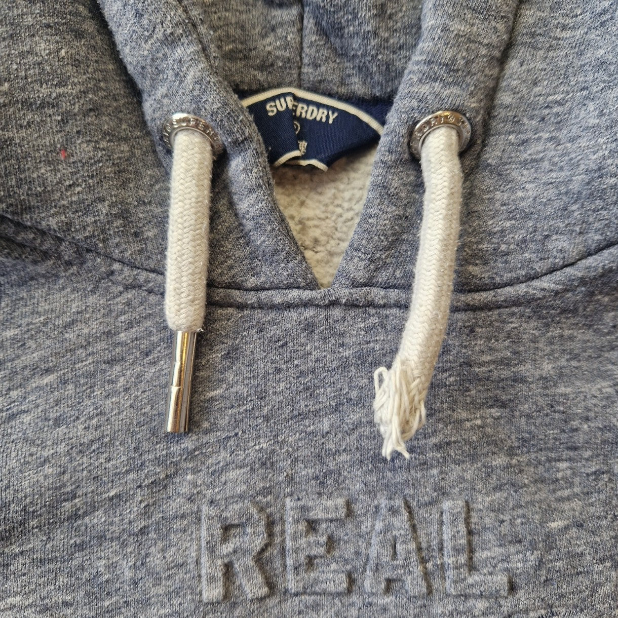 A grey Superdry pullover hoodie for boys featuring an embossed logo and branded metal aglets.