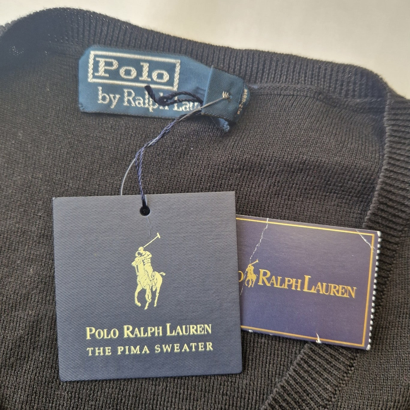 A black Polo Ralph Lauren V-neck cotton sweater with brand tags attached.