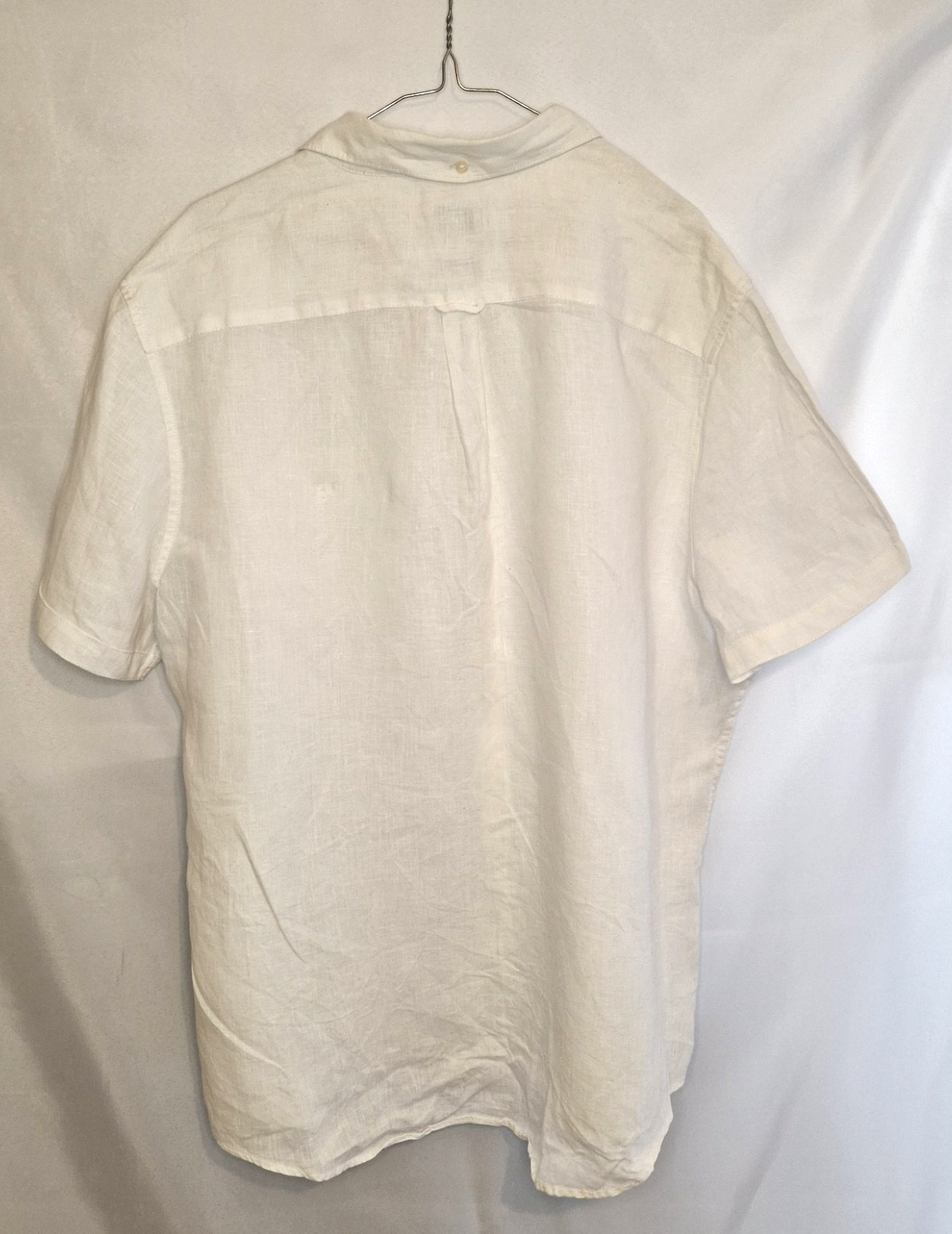 A white short-sleeved button-down shirt with a blue floral print, shown from the back.