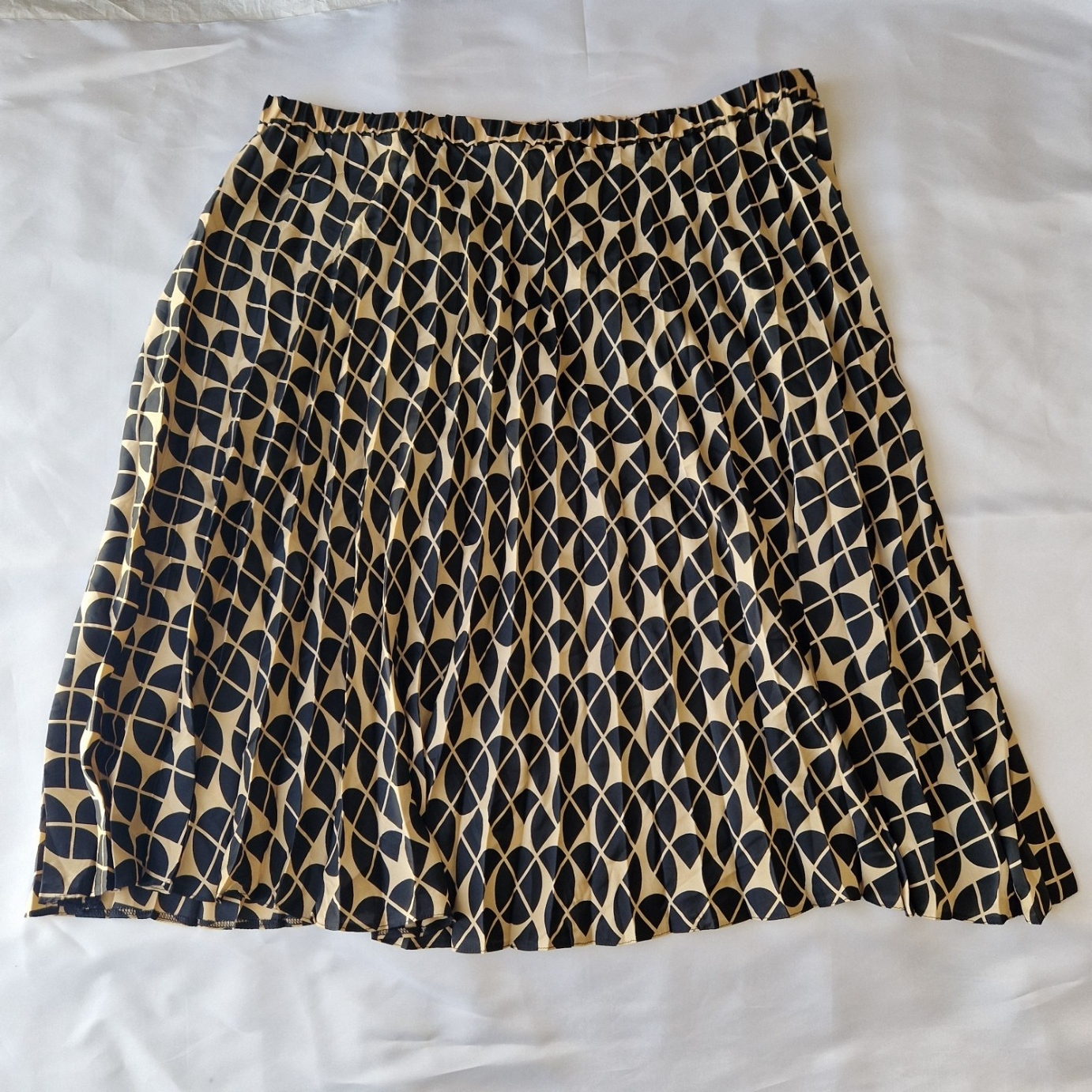 A knee-length, high-rise A-line skirt by George featuring a black and metallic gold geometric print.
