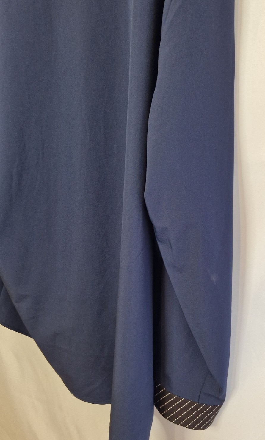 A blue long-sleeve shirt with a patterned contrast trim on the cuff.