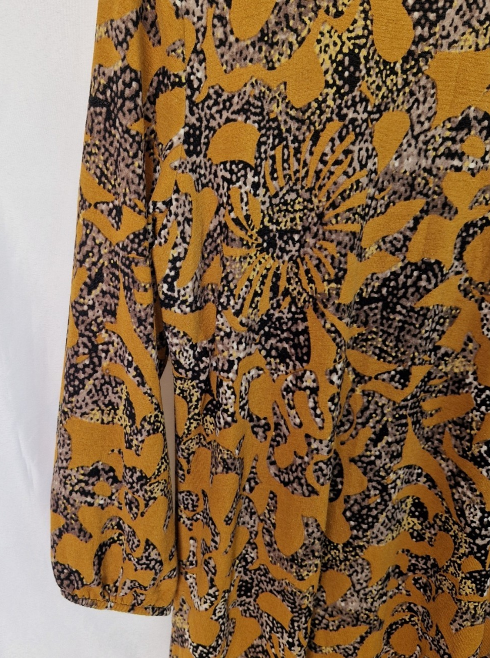 A long-sleeve yellow tunic top featuring a black and grey abstract floral print.