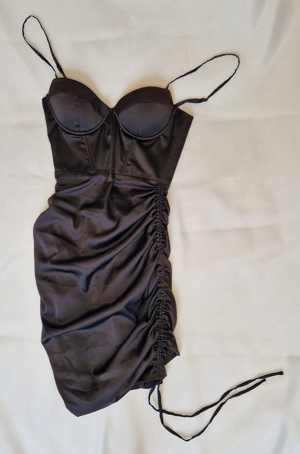 A black satin bodycon mini dress with a corset-style bodice and a ruched side detail.