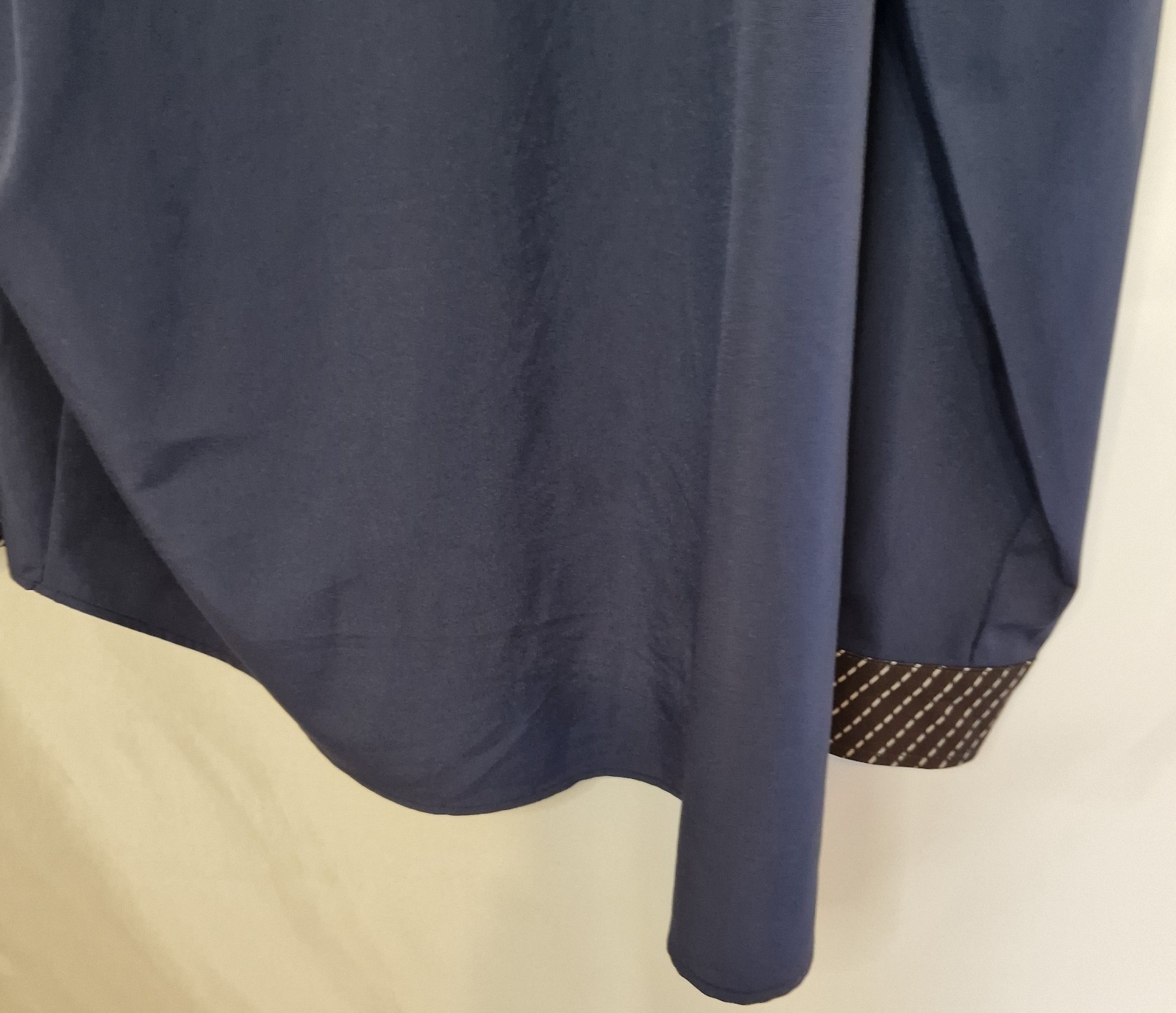 A blue long-sleeve satin shirt featuring a patterned contrast trim on the cuff.