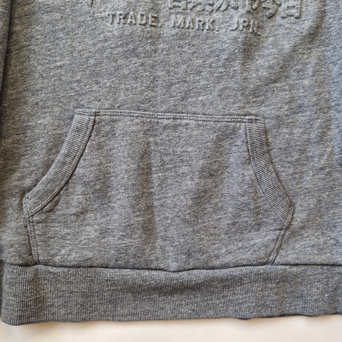 A grey Superdry boys pullover hoodie featuring an embossed logo and a front kangaroo pocket.
